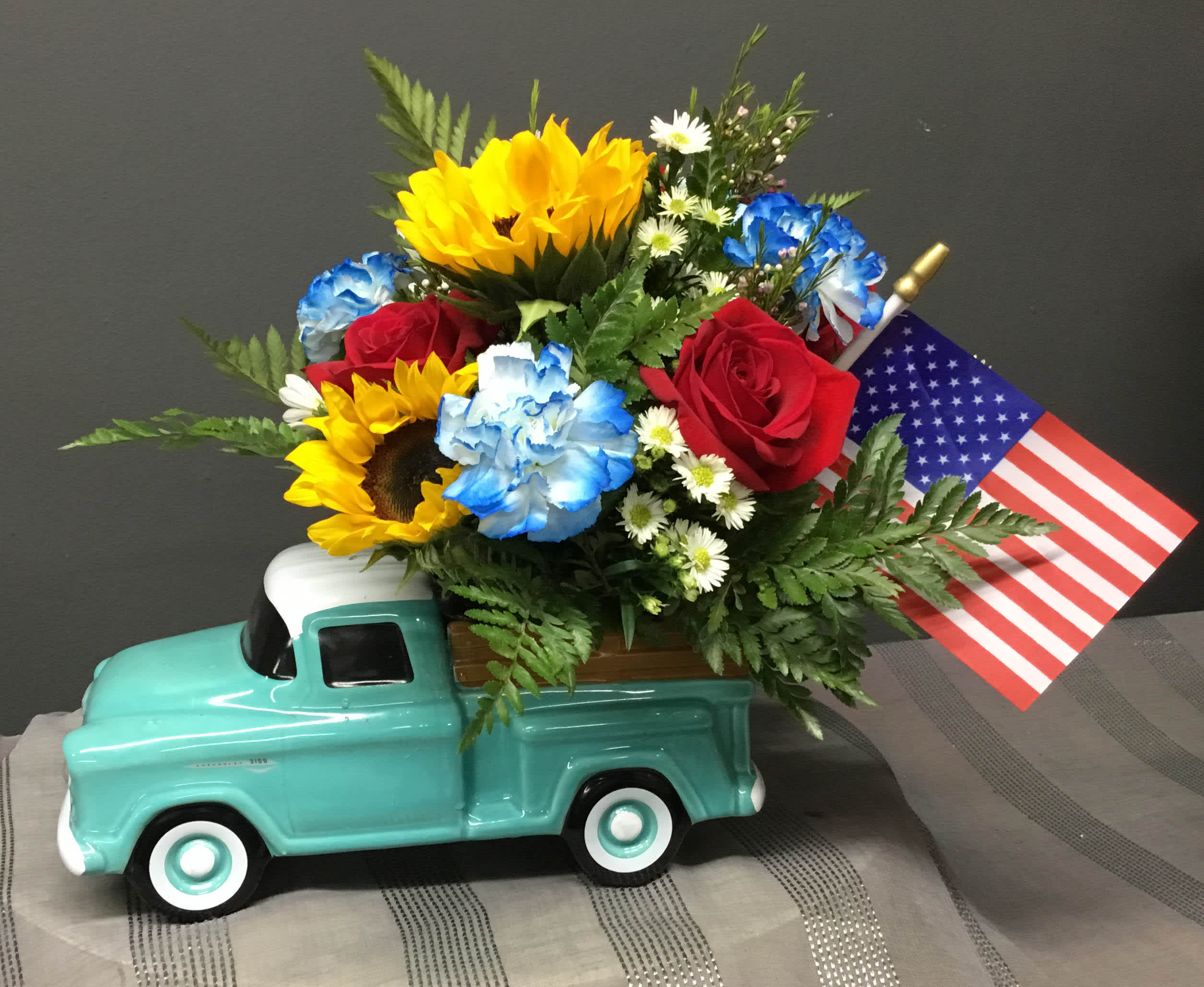 A Classic for Dad - Red, White and Blue Flowers mixed with and american flag in a ceramic chevy pick up. Perfect for Father's Day or the 4th of July!