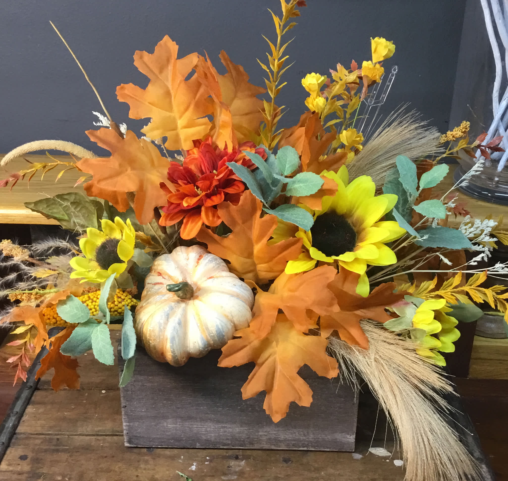 Autumn floral arrangement with sunflowers, orange blooms, and a decorative pumpkin
