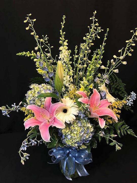 Whimsical flowers for the Funeral Service - An assortment of imported including Holland flowers plus unique seasonal flowers you won't find anywhere else arranged in a tall glass vase.  This is large enough to make a nice display at a funeral or memorial service.  Very pretty and cheerful arrangement that can also be taken home after the service so the family can enjoy them.
