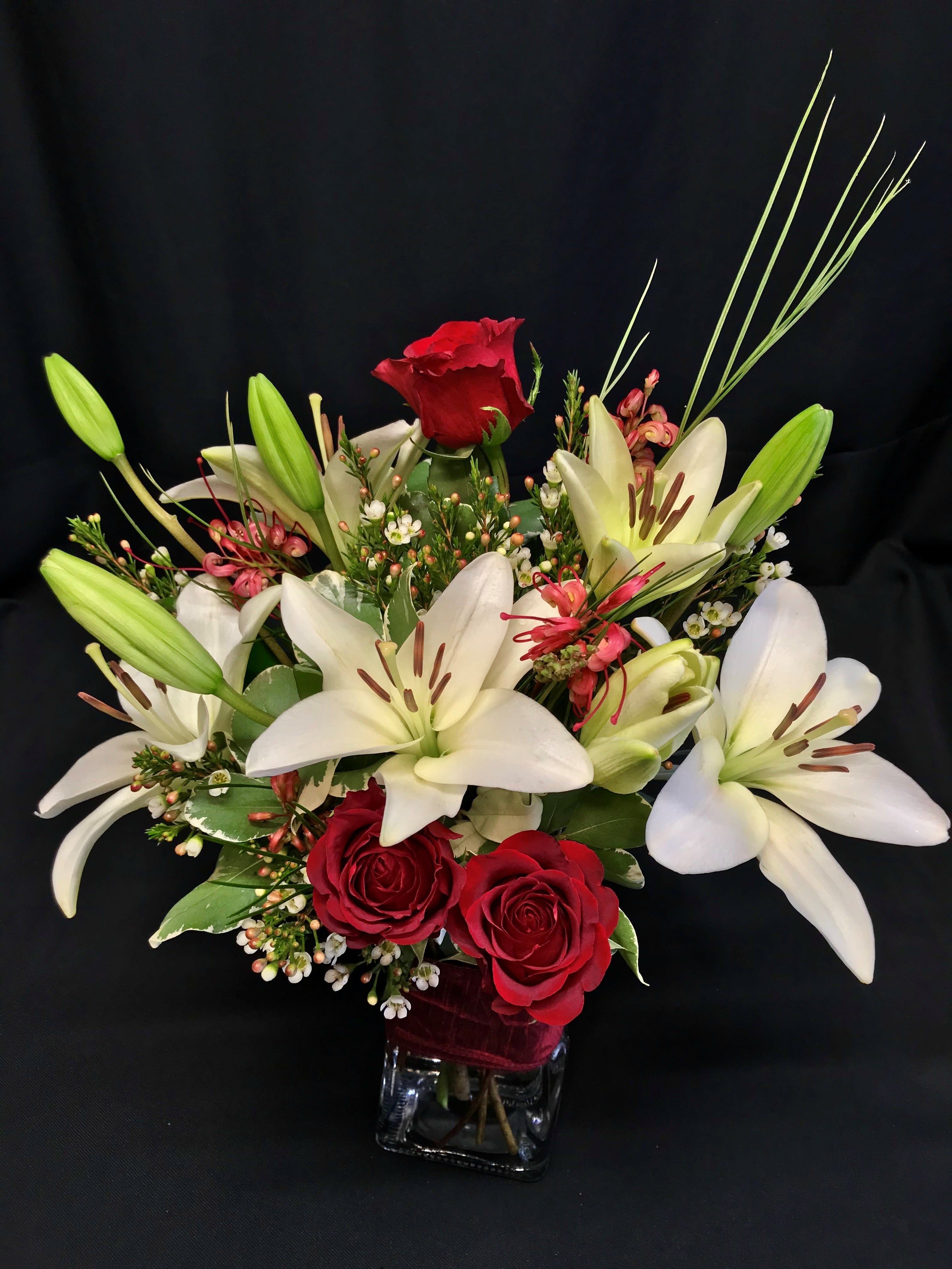 Winter Medium Mixed Bouquet Lilies and Roses - 3 Gorgeous Red Roses with Large Asiatic lilies and accent flowers for your sweetheart or for the holidays.   Flowers may arrive in a slightly more closed budded state but will open nicely after delivery.  Assortment and lily color may consist of different holiday colors based on availability.  Modern glass vase and ribbon clutch.  Beautiful simple modern design for your love.