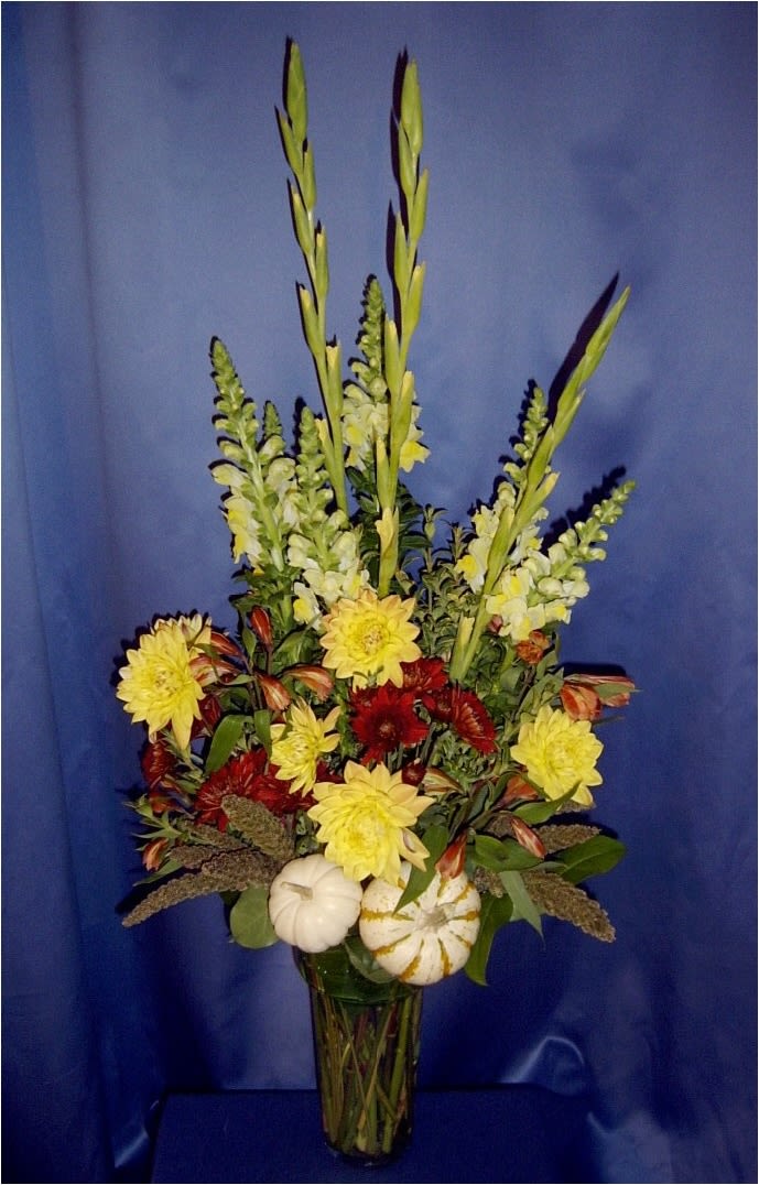 Tall rust mum Autumn arrangement with pumpkins - Elegant fall color and sweet millet and mini pumpkin accents at the base of a tall handsome glass vase.*  Order in advance to ensure choice autumn colors.  