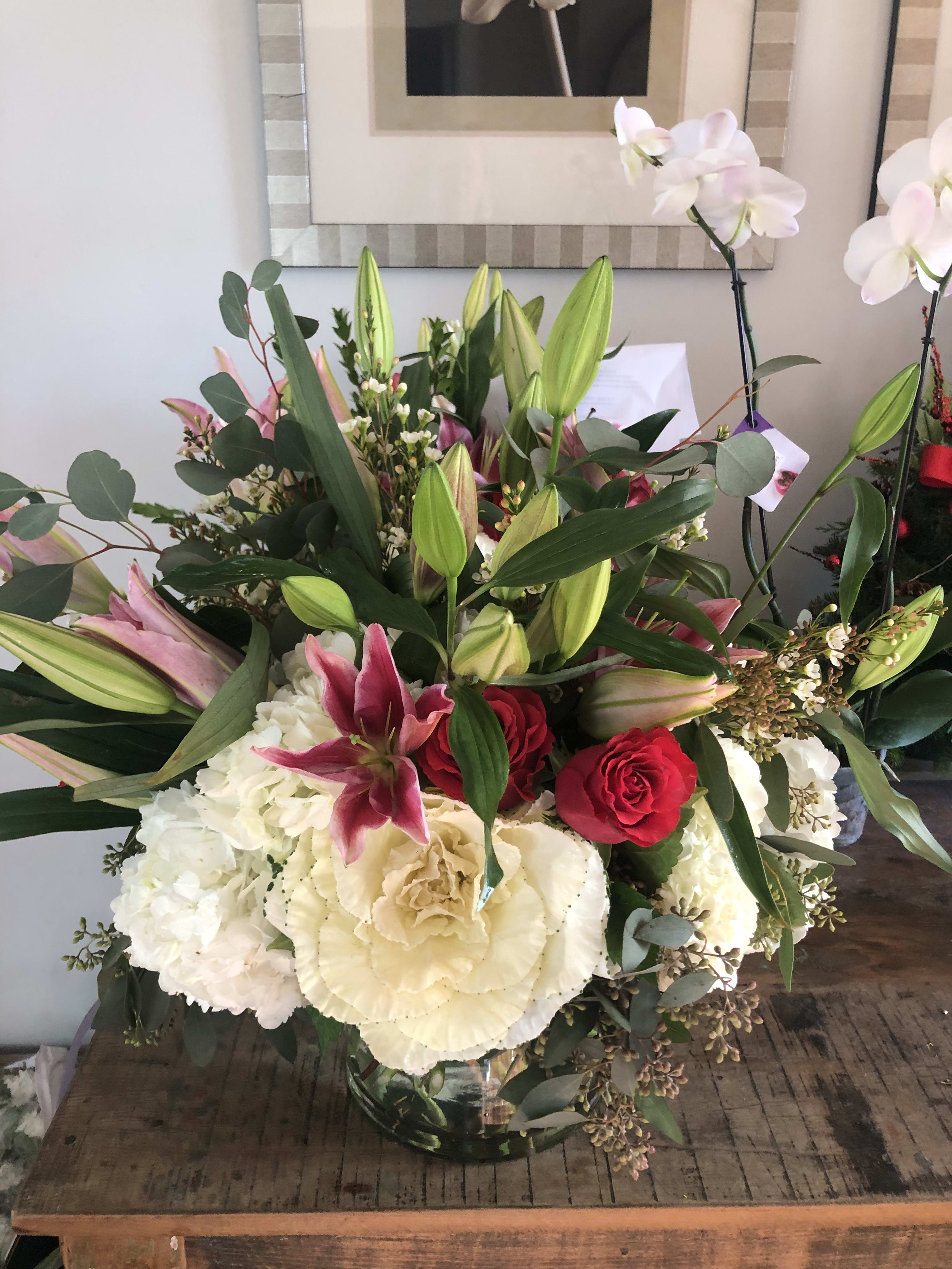 Large bouquet of lilies, roses, hydrangeas, and orchids in a glass vase