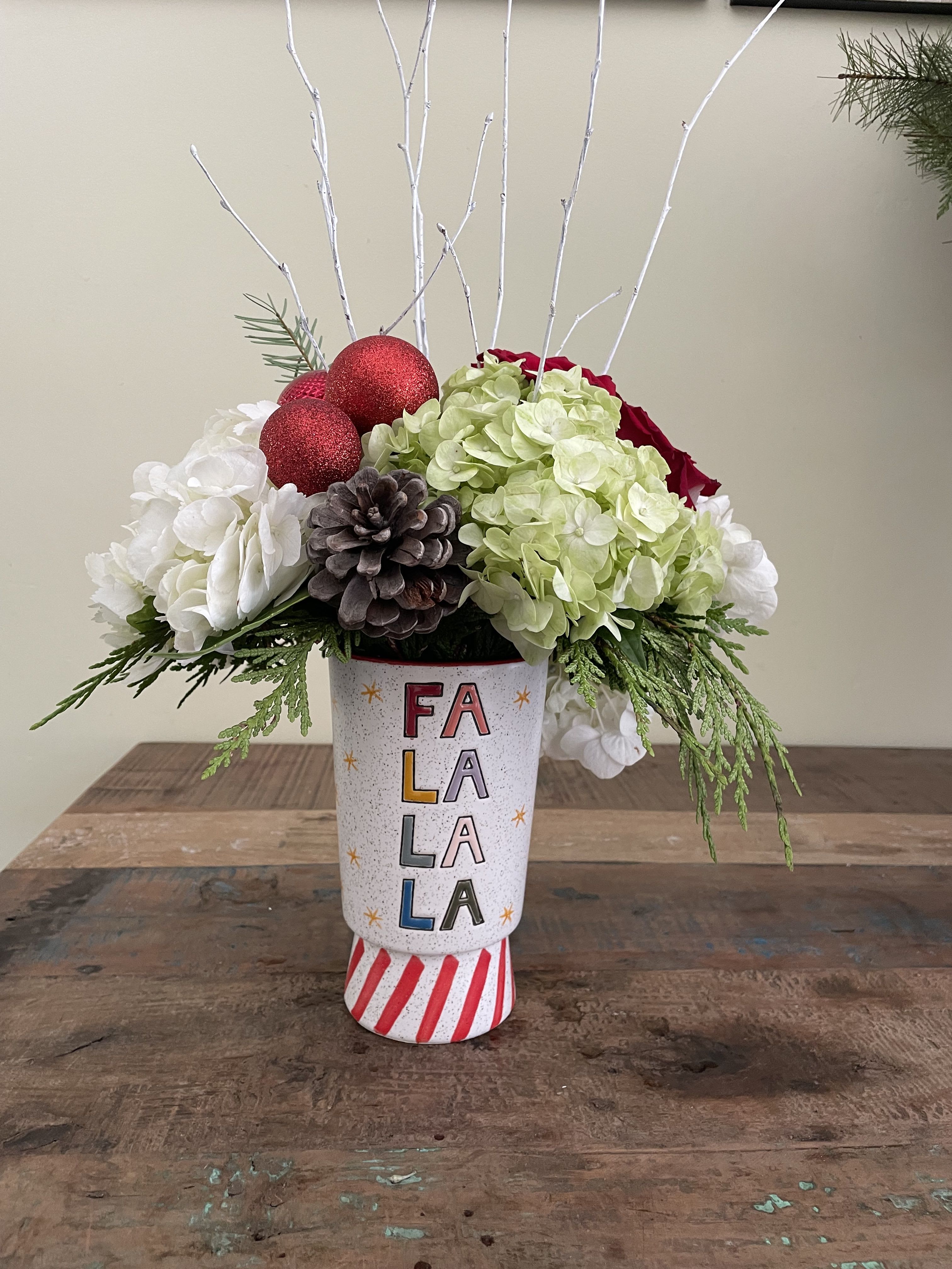 Holiday floral arrangement in a decorated vase with red ornaments and white branches
