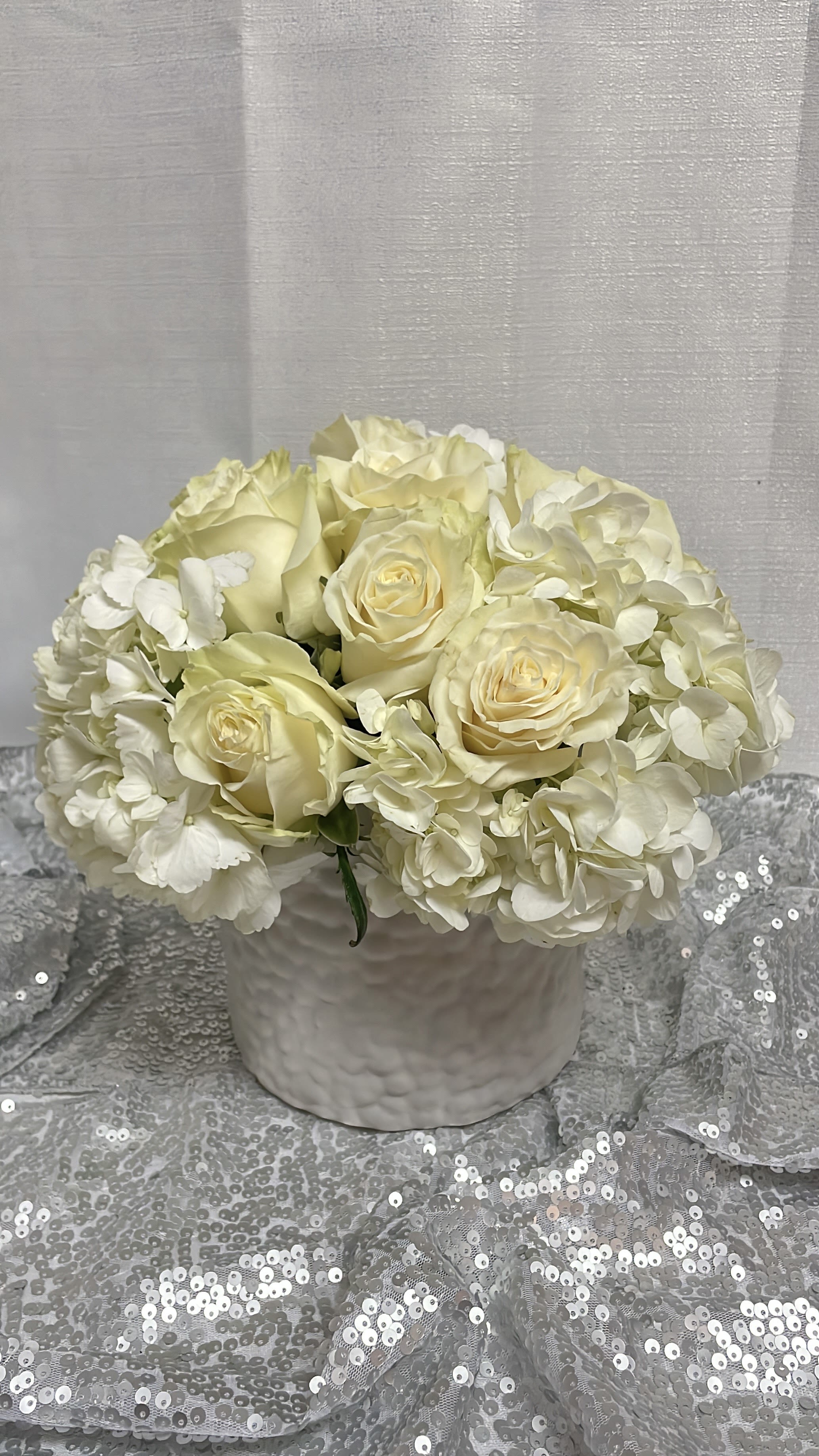 Cream roses and white hydrangeas in a white vase
