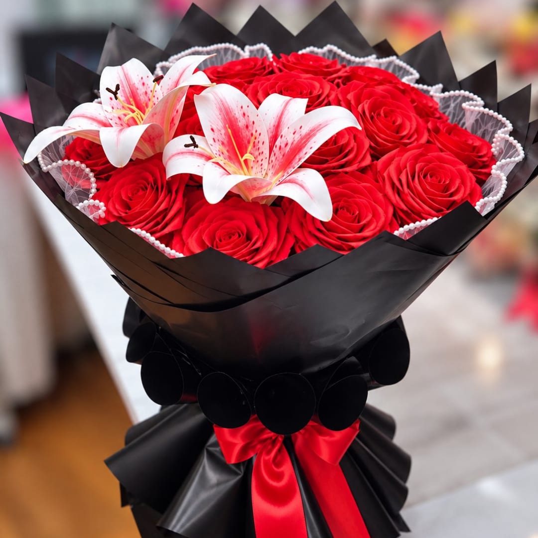 Bouquet of red roses with two white lilies in black wrap