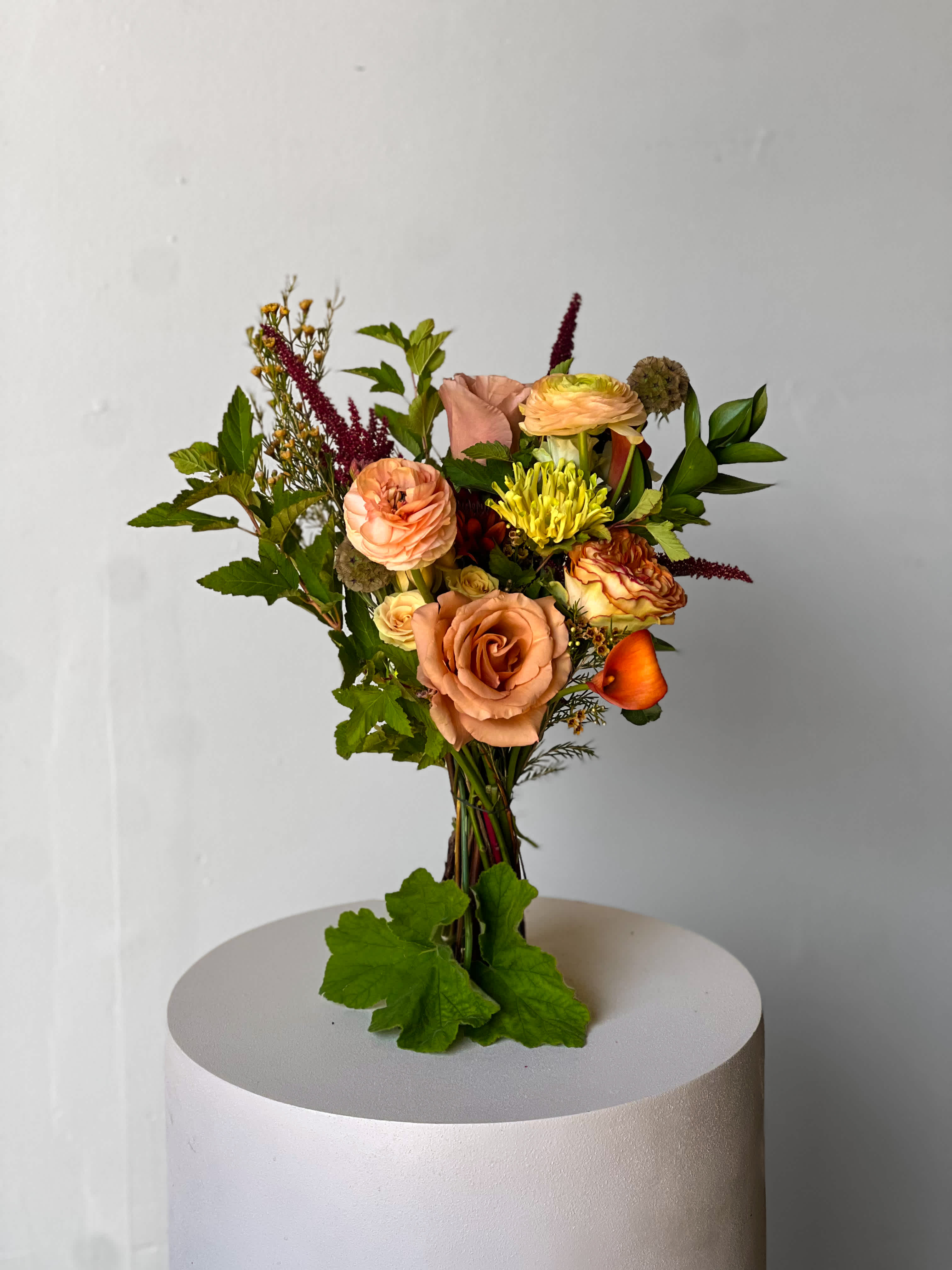 Mixed bouquet of peach and yellow flowers with greenery