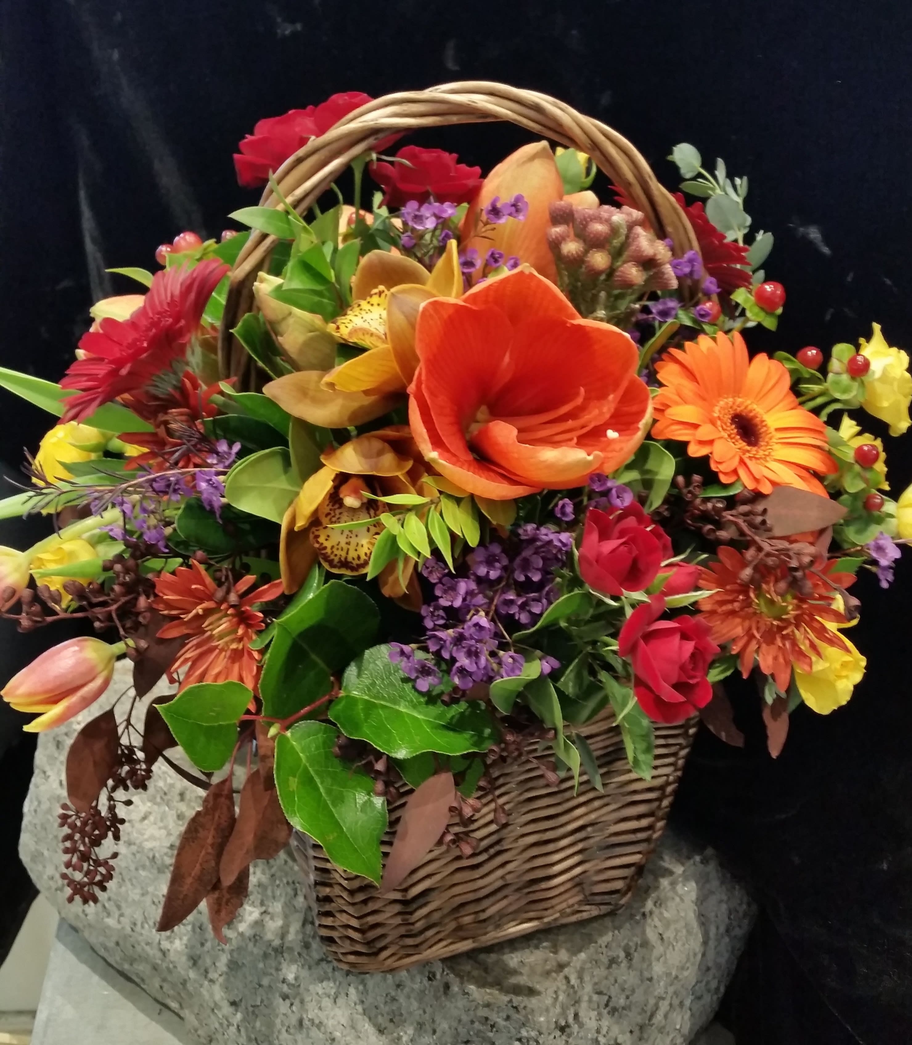 Basket arrangement with orange, red, and purple flowers