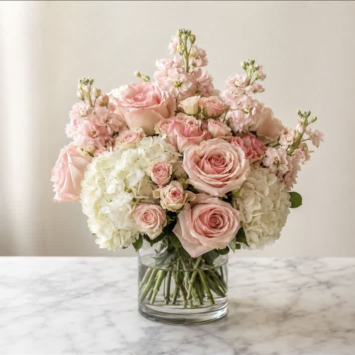 Pink roses and white hydrangeas arranged in a clear glass vase