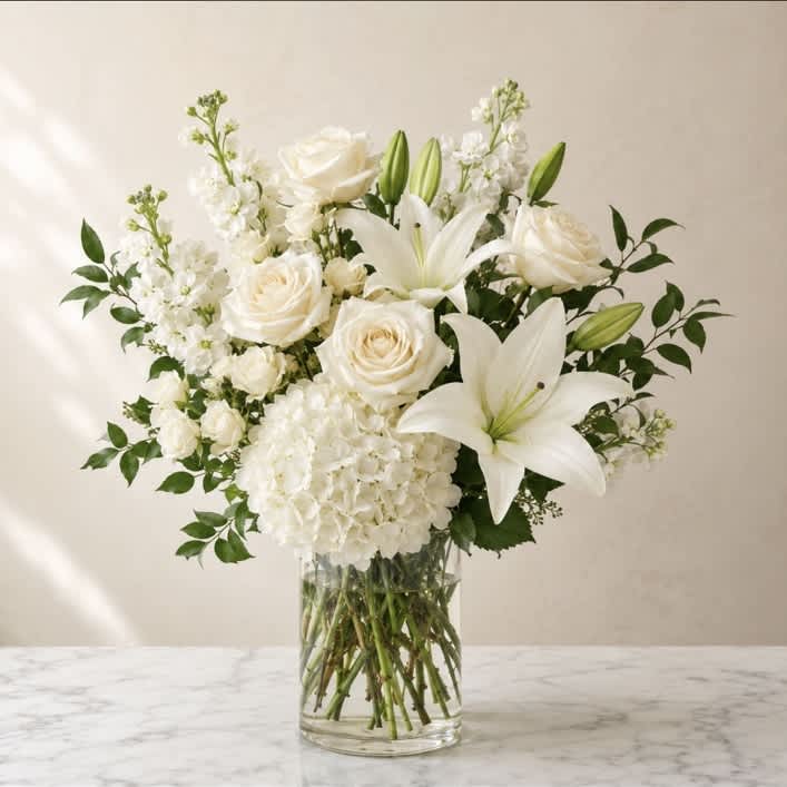 White roses and lilies arranged in a clear glass vase