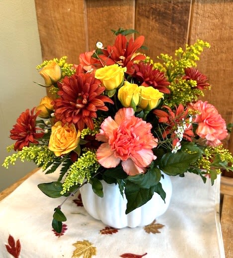 Autumn bouquet of red, yellow, and pink flowers in a white vase