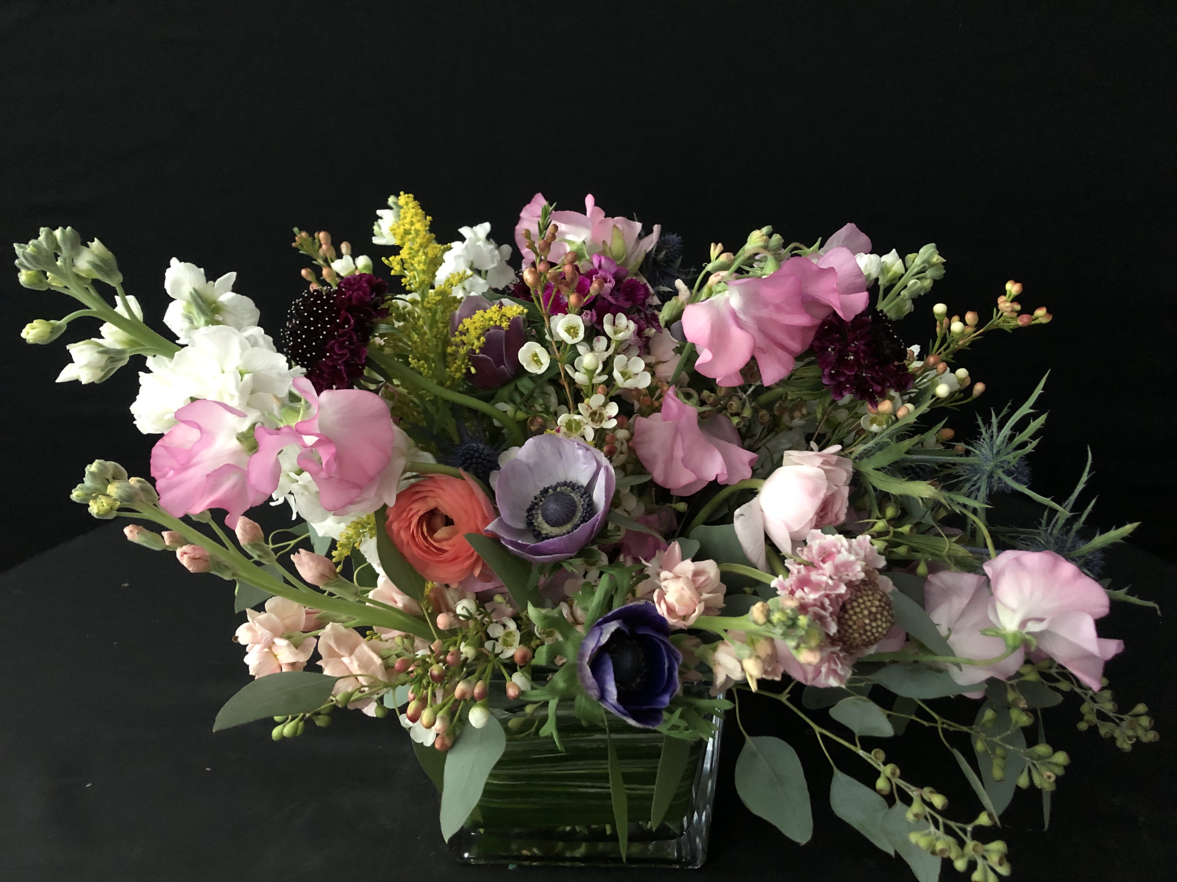 Designers Choice Texas Wild Flower. SOLD OUT FOR MOTHER’S DAY. - We will design with the flowers of the day~ this designers style is what we call "Texas wild flower." Colors and flowers will vary since it is Designers Choice, but it will look and be Texas wild flower. You can always ask us for your favorite colors and we will do our best!  Upgrading does mean more flowers, lisianthus and other wild flowers of the season. We do support local farms. They inspired this beautiful design.  When you order online you will receive several emails until order has been completed and delivered by the designer who put it together.  We are more than just flowers; we are an experience you will love. This is designed in a 5 x 5 cube good for a desk, side table, night stand and cocktail table. 