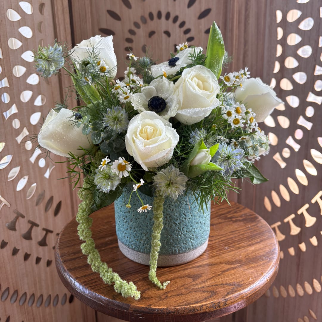 White roses and small daisies in a blue vase