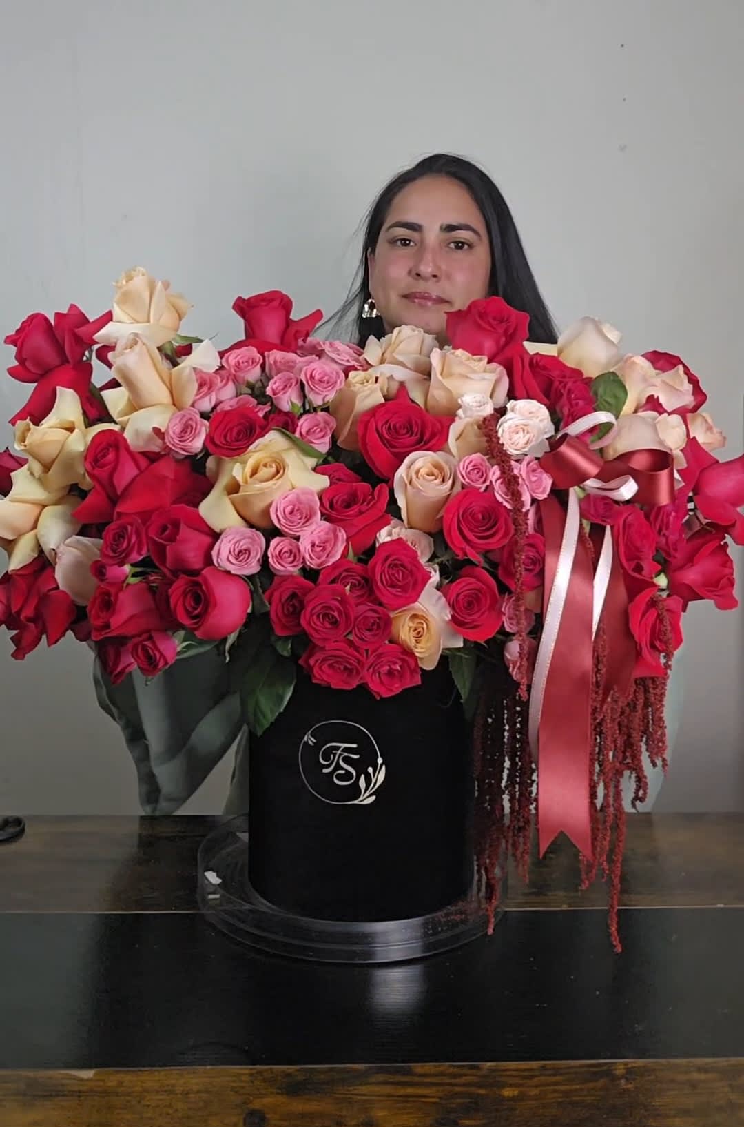 Large arrangement of red, pink, and cream roses in a black hat box