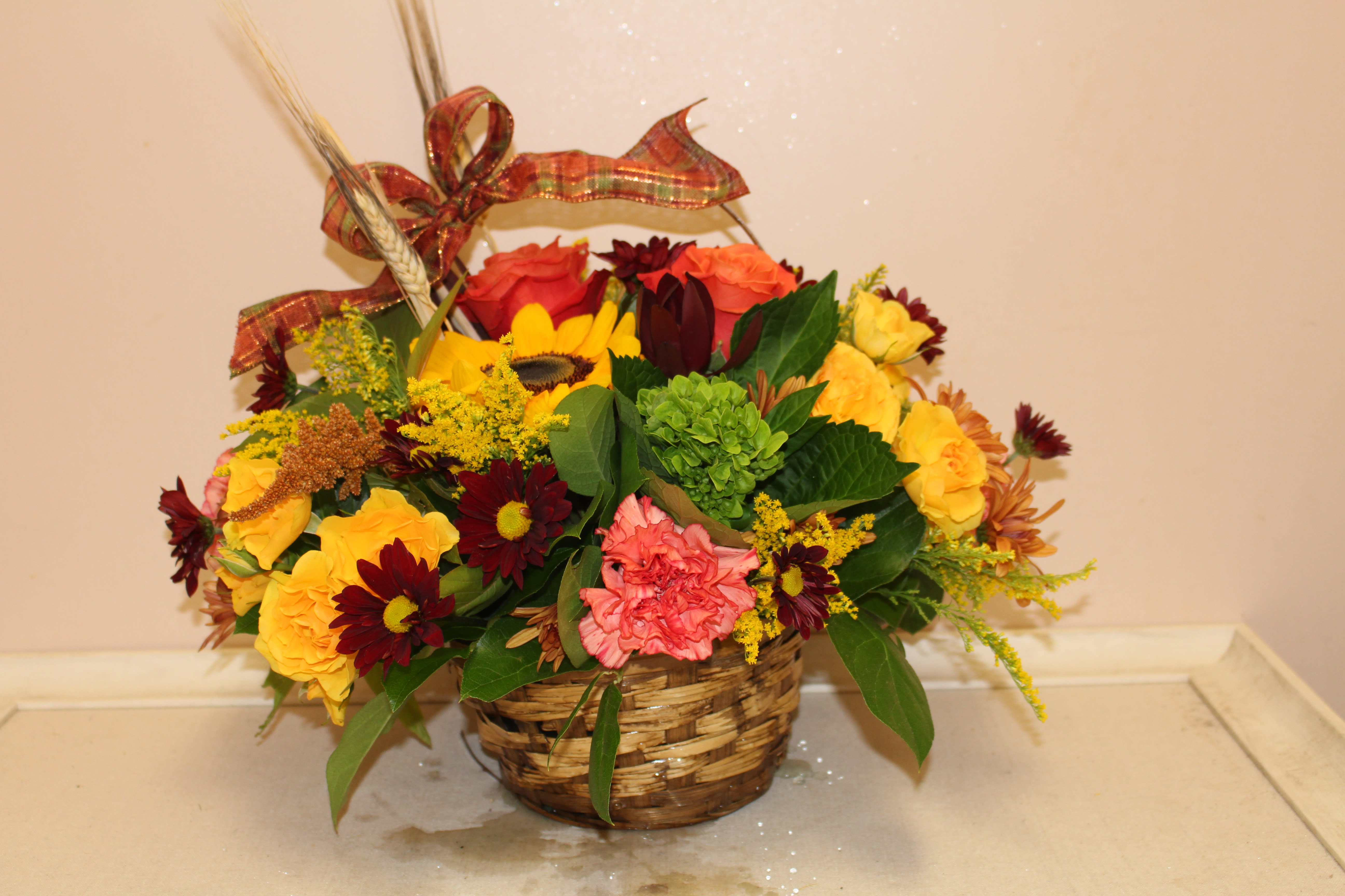 Autumn abundance - send the colors of fall for any occasion.  A Mix of roses, poms and sunflowers are perfect in this basket.  