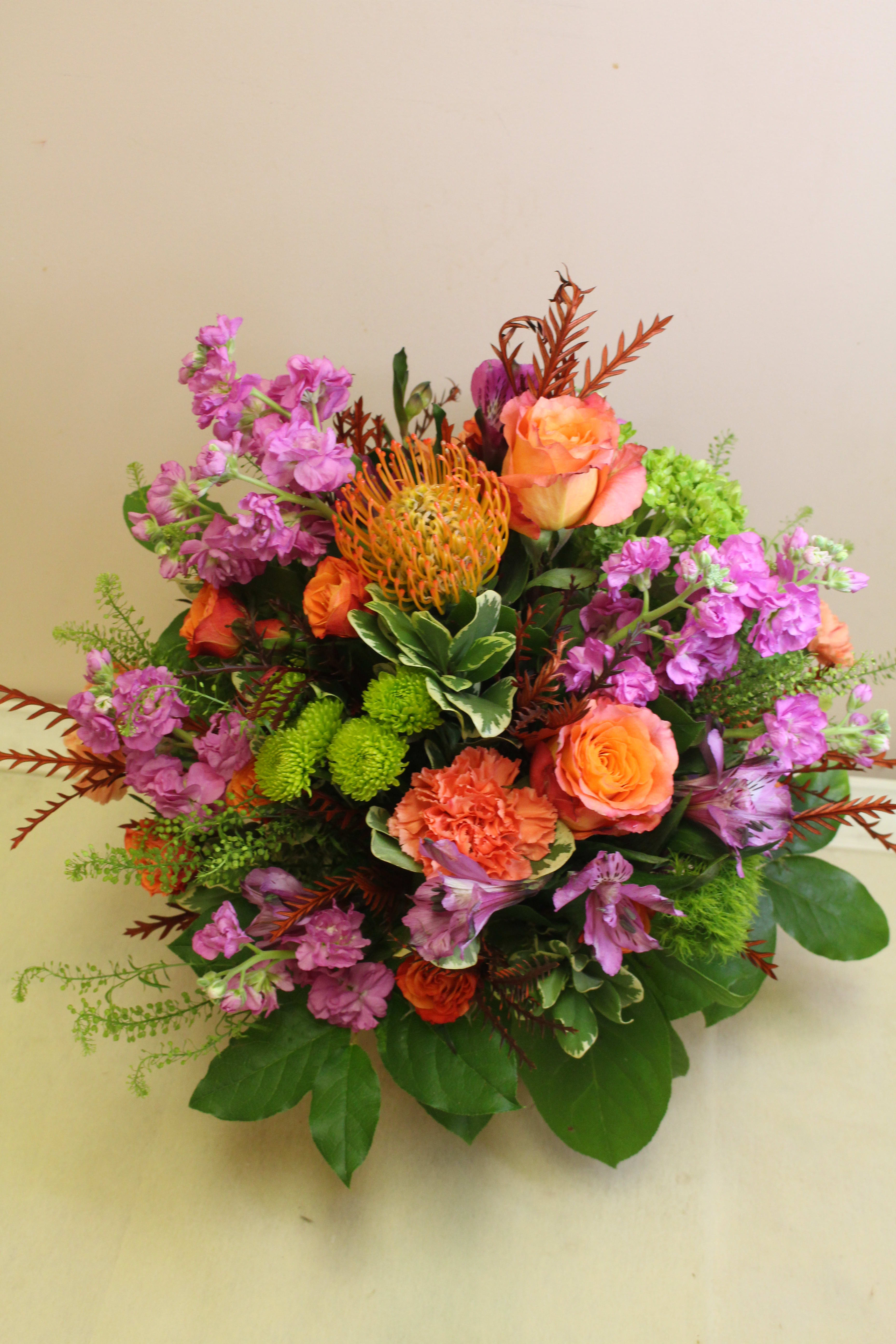 Mixed bouquet with orange roses, purple blooms, and green accents
