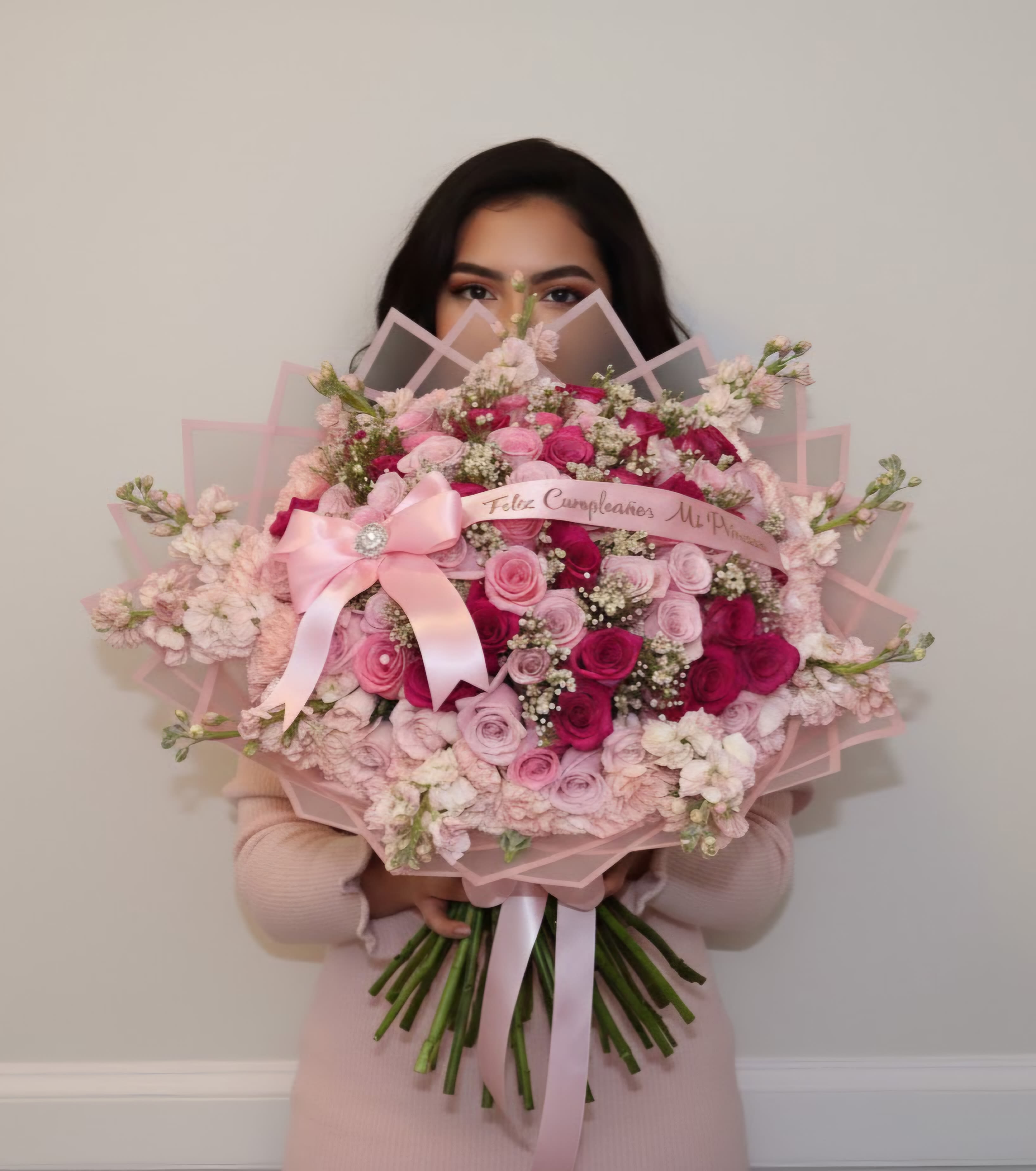 Woman holding a large pink bouquet of roses with a ribbon bow