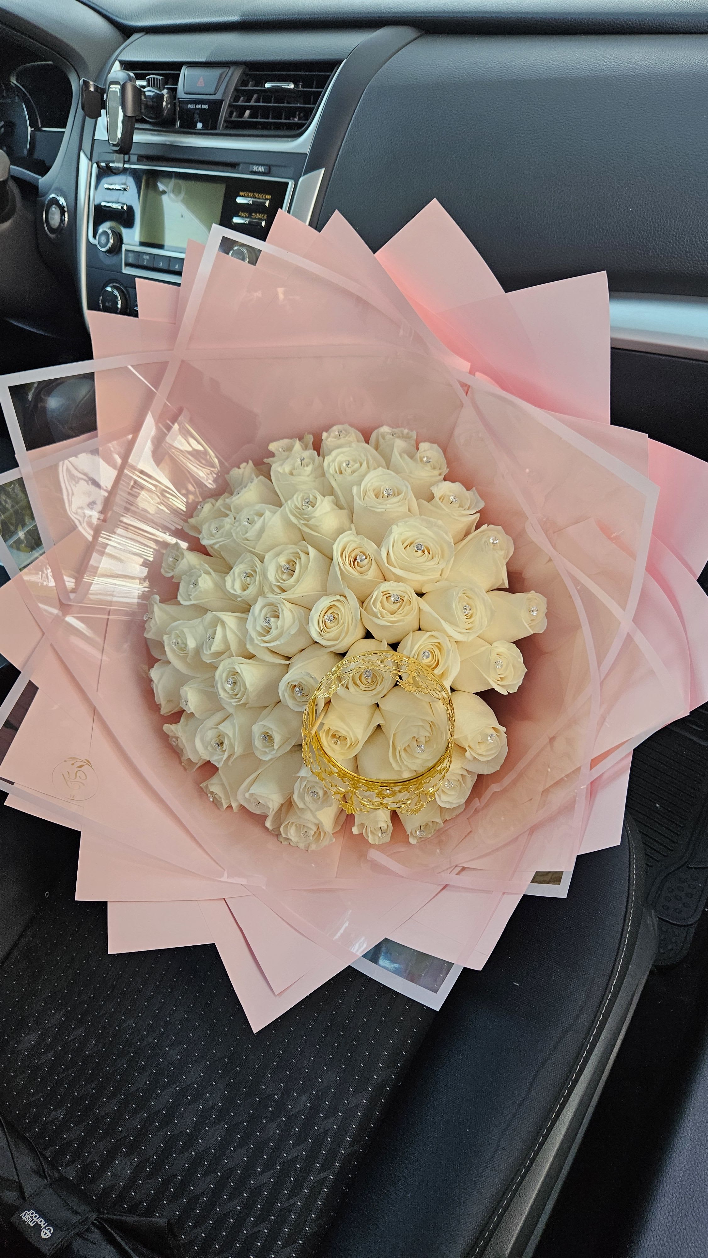 Bouquet of white roses wrapped in pink paper with a gold handle