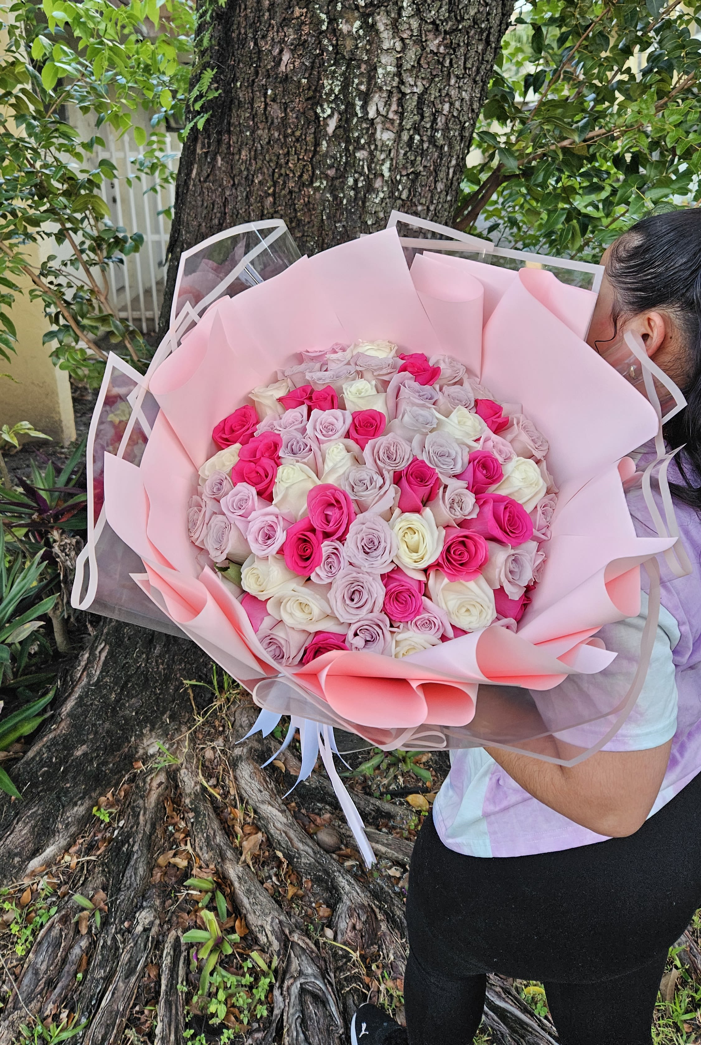 Large bouquet of pink, lavender, and white roses wrapped in pink paper