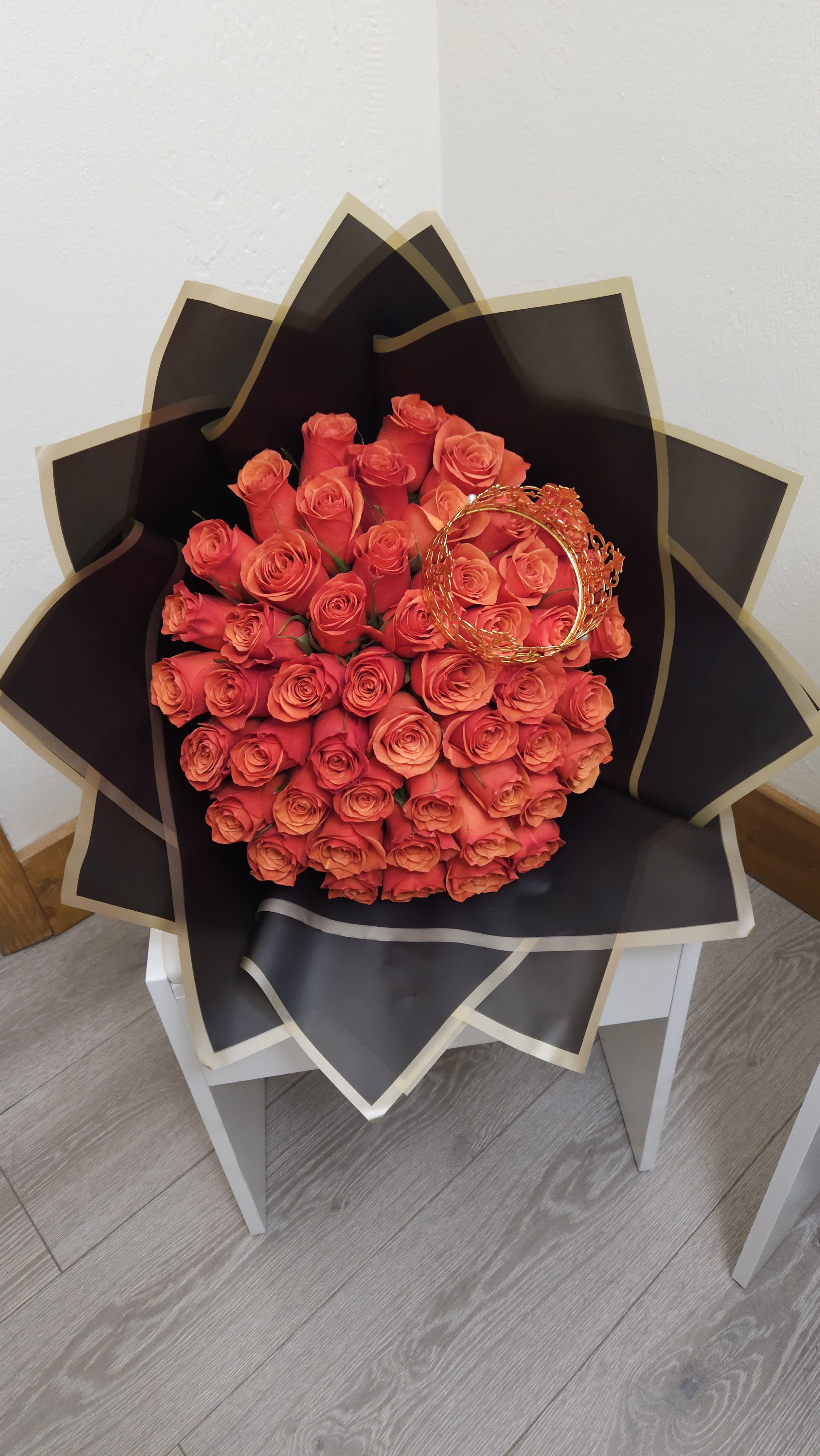 Bouquet of orange roses wrapped in black paper with gold trim