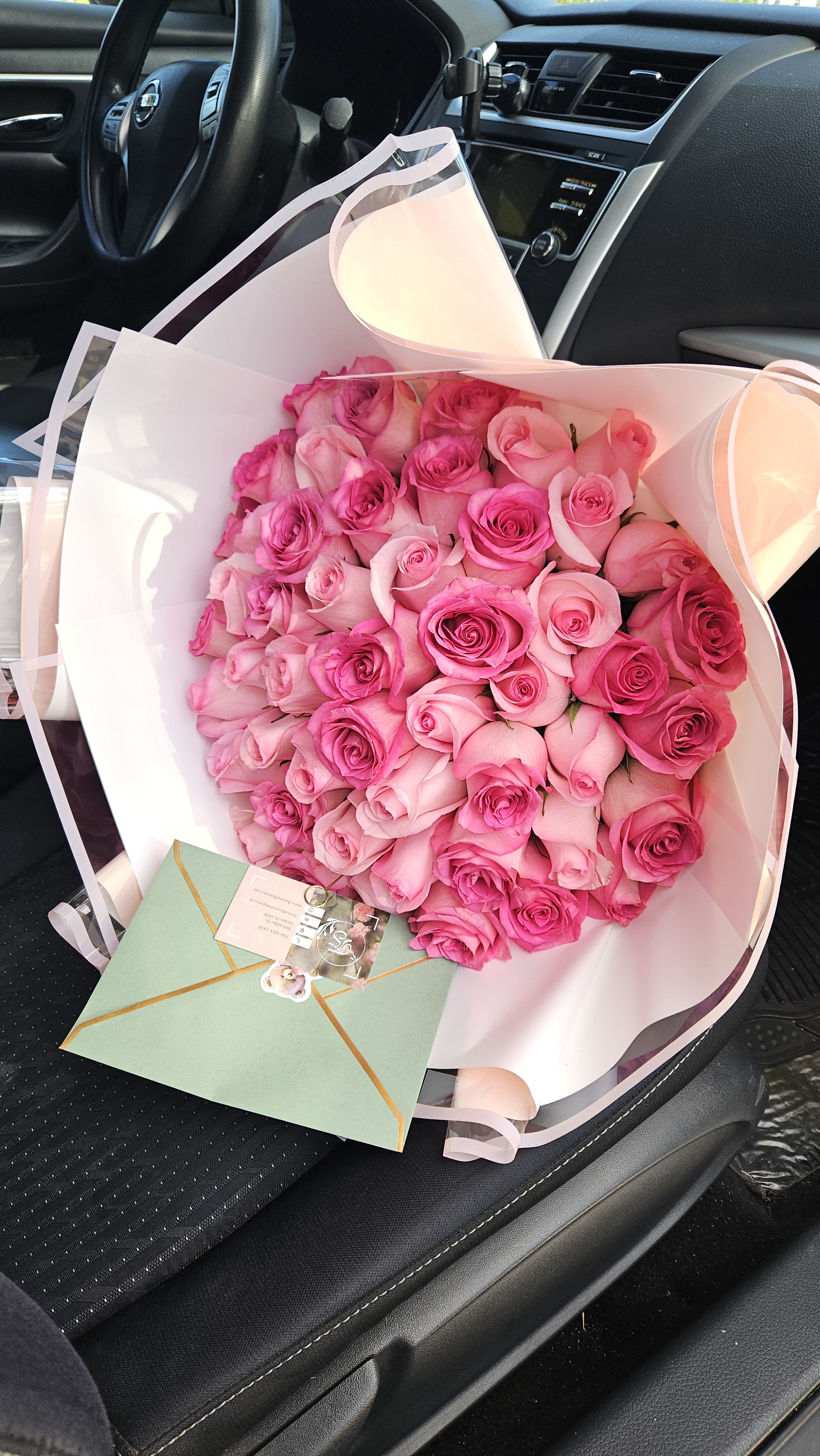Bouquet of pink roses wrapped in white paper with a card