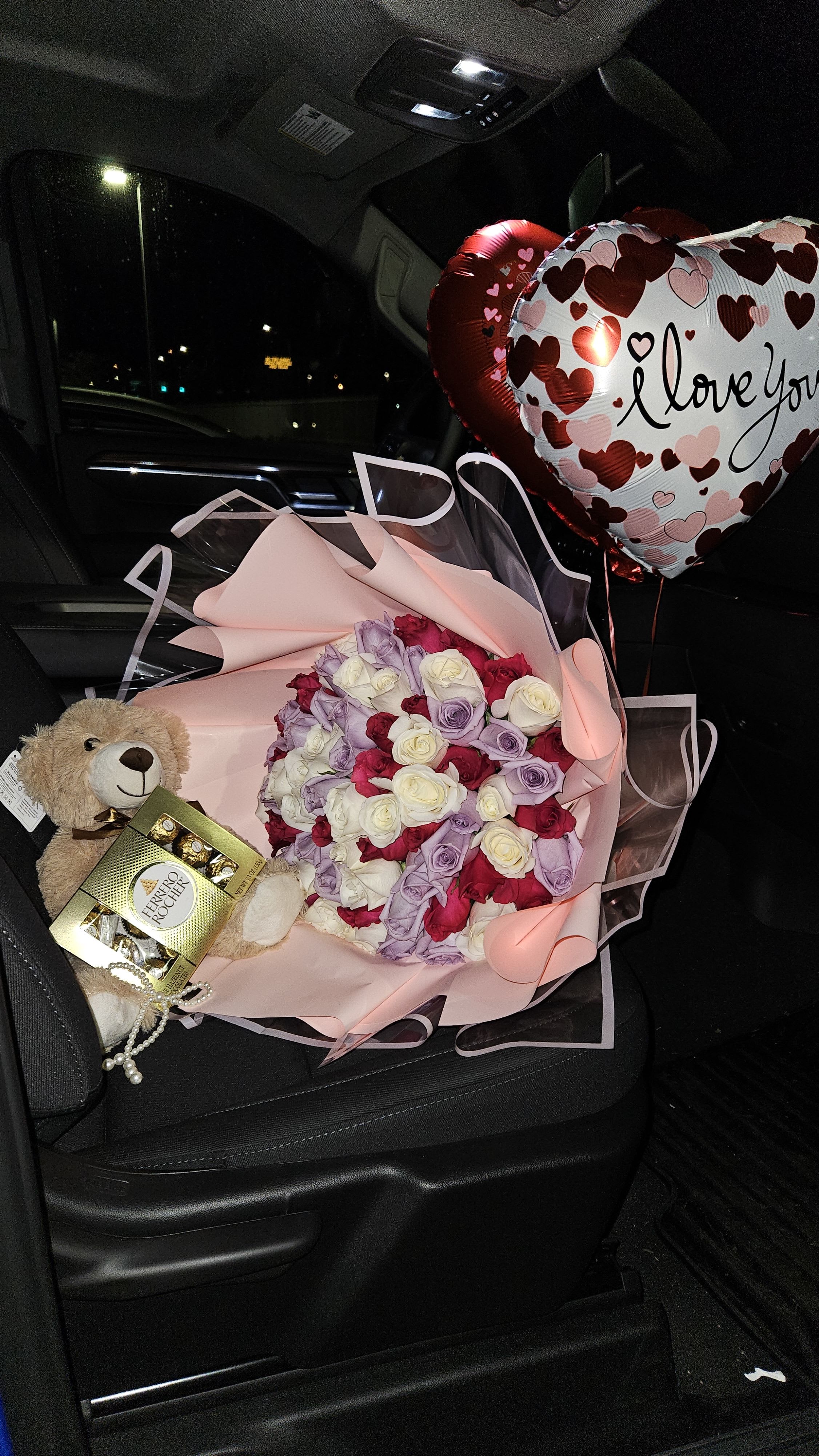 Bouquet of pink, white, red, and lavender roses with heart balloons and a teddy bear