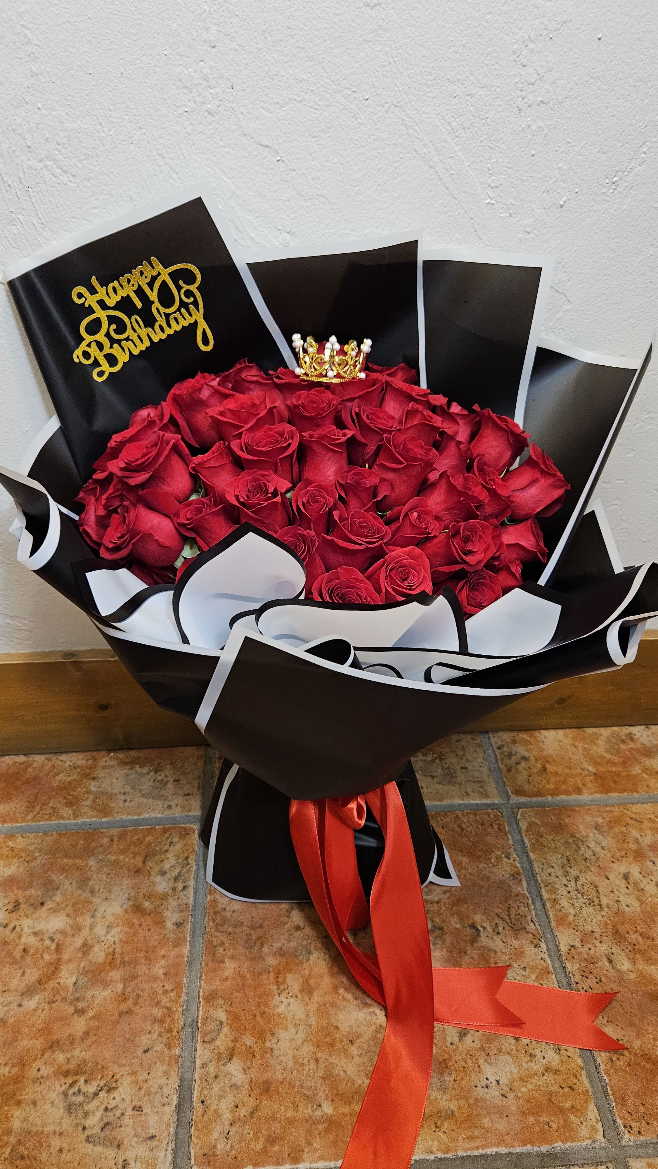 Bouquet of red roses in black and white wrap with a birthday topper