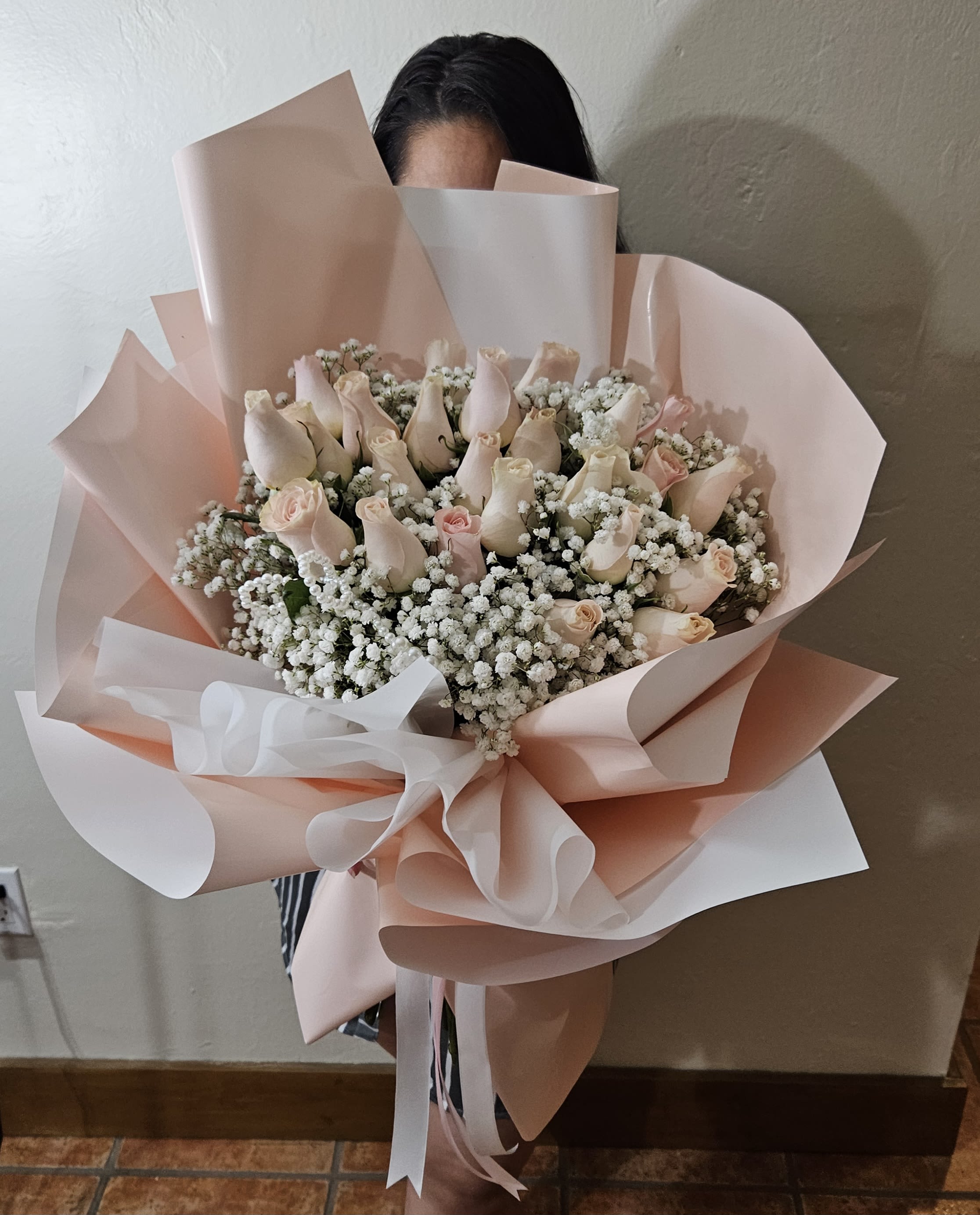 Bouquet of pale pink roses and white baby's breath wrapped in blush paper