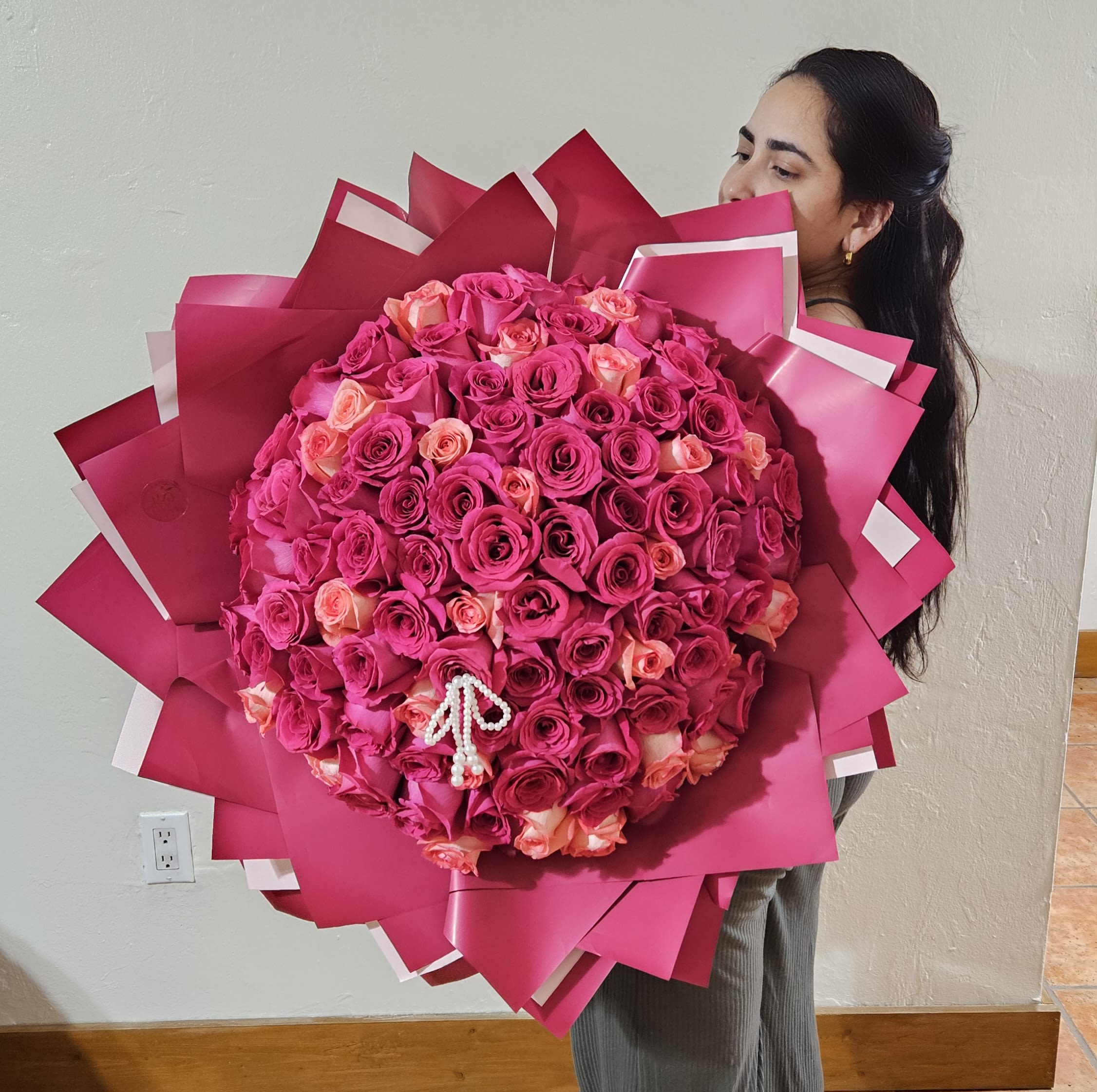Large bouquet of pink and peach roses wrapped in bright pink paper