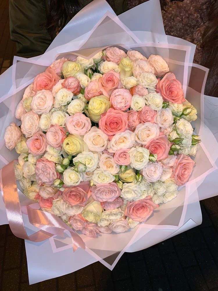 Large bouquet of pastel roses wrapped in pink paper