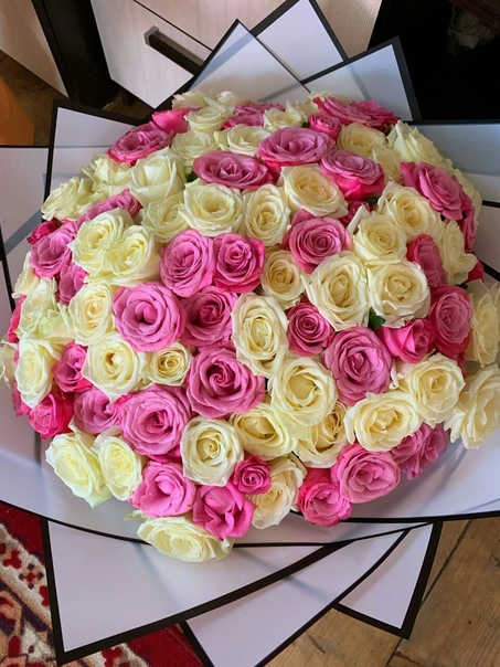 Bouquet of pink and cream roses wrapped in black-edged paper