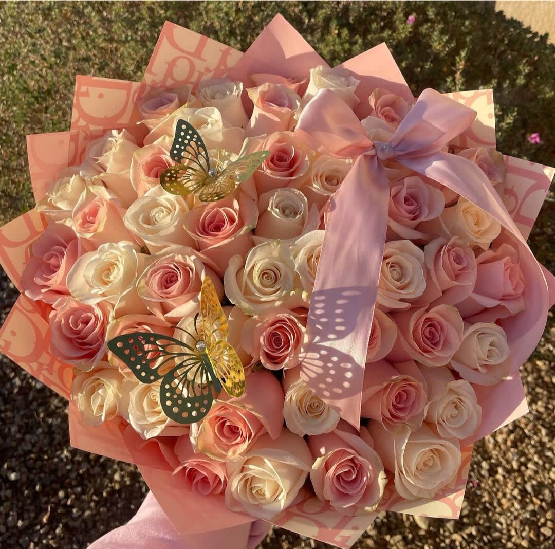 Bouquet of pale pink and cream roses with a pink ribbon and butterfly decorations