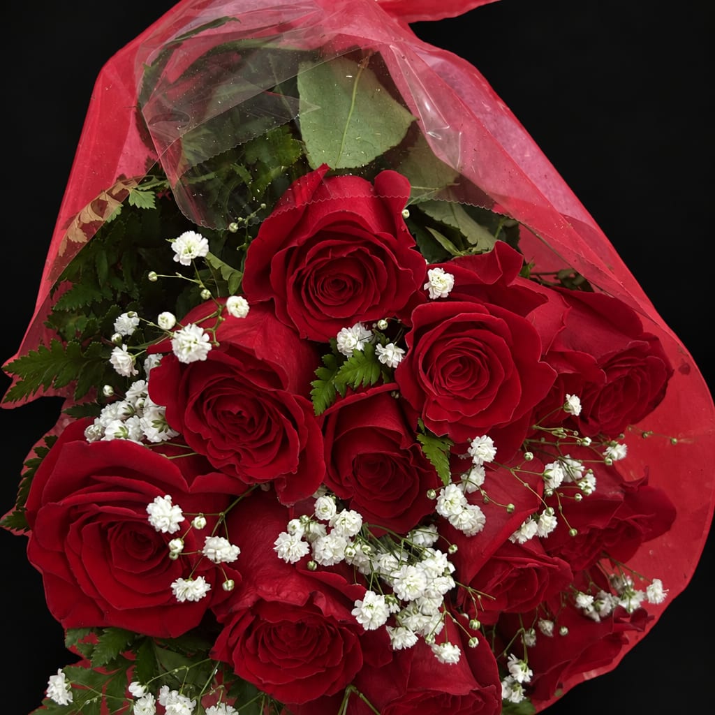 Bouquet of red roses with small white filler flowers wrapped in red paper