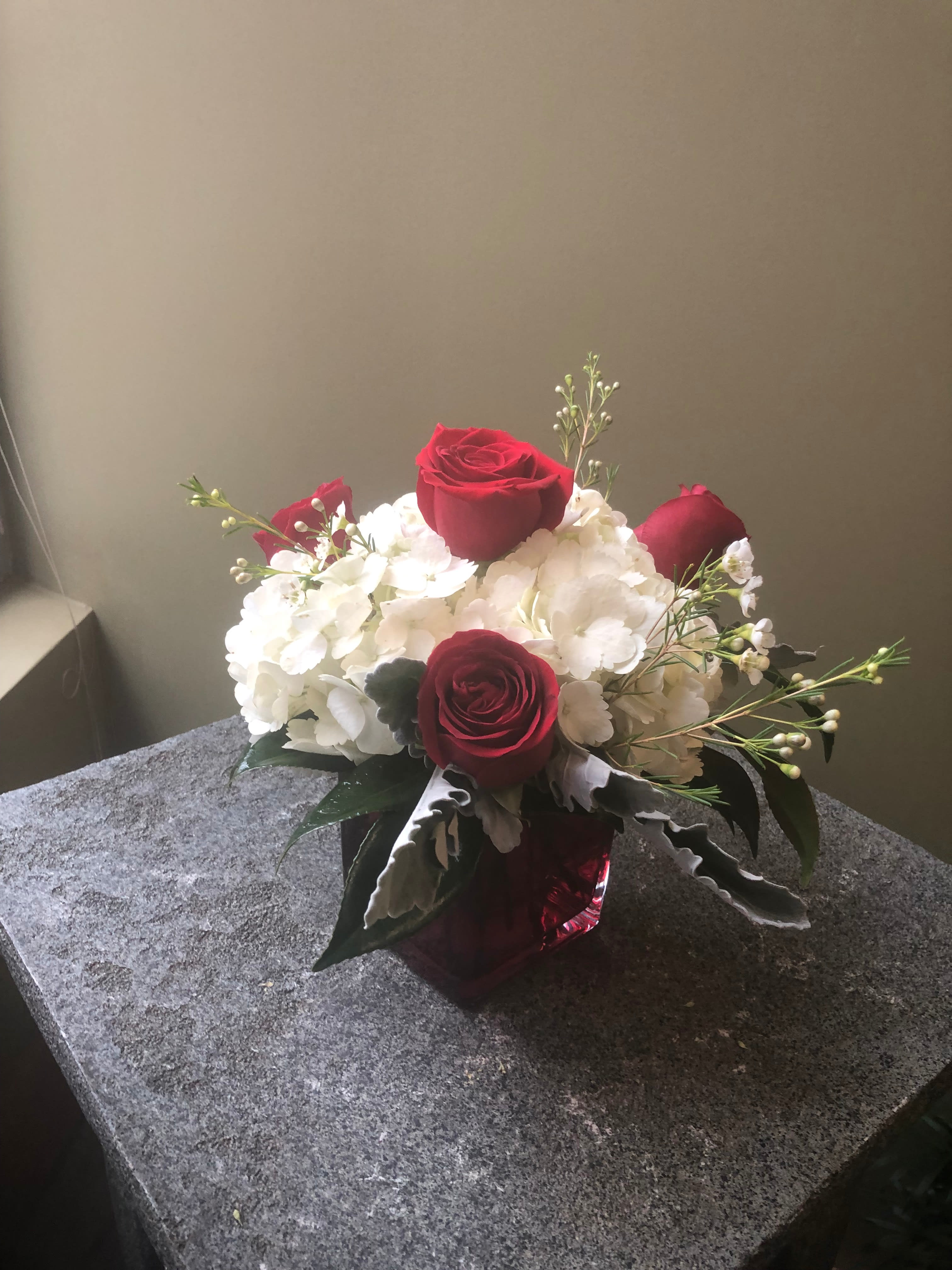 Red roses and white hydrangeas in a red glass vase