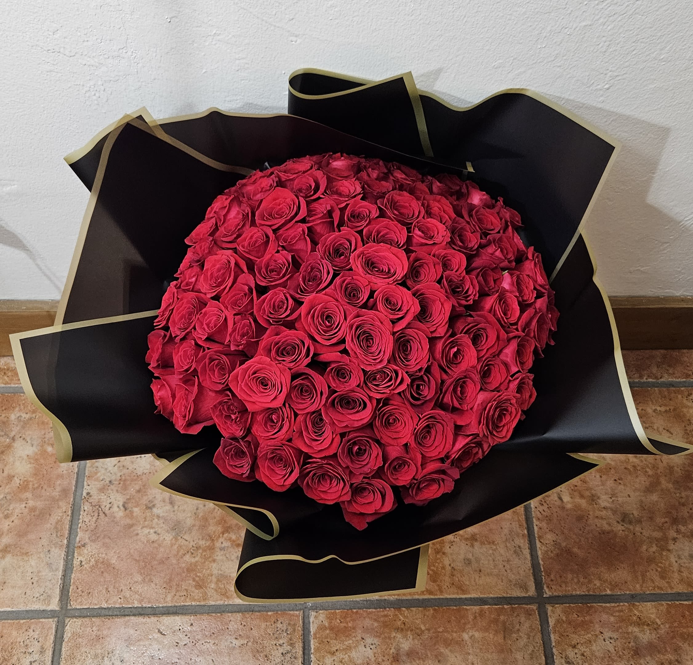 Large bouquet of red roses wrapped in black paper
