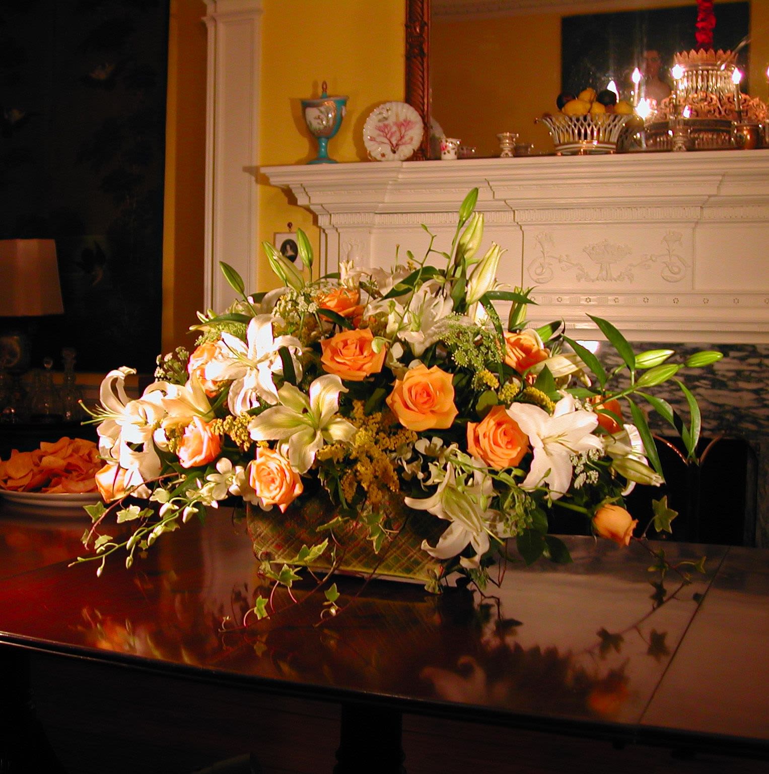 Orange roses and white lilies arranged in a low centerpiece