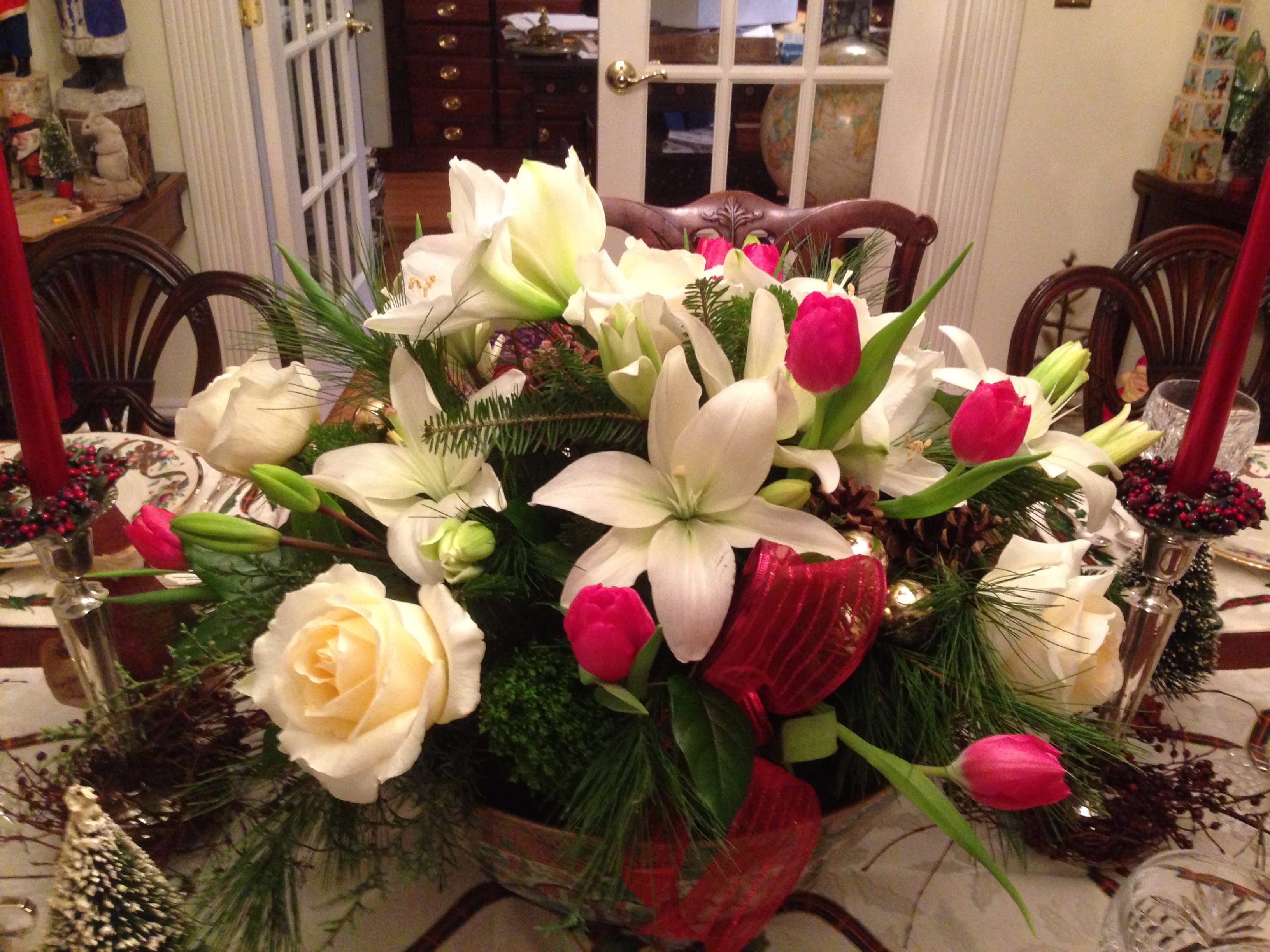 White lilies and pink tulips arranged in a low centerpiece with roses
