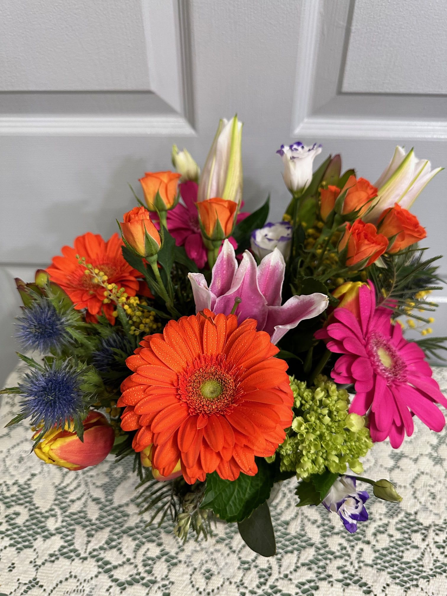 Bright mixed bouquet with orange gerberas, roses, lilies, and pink blooms