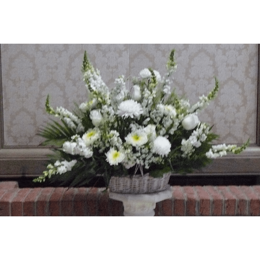 White floral arrangement in a woven basket on a pedestal