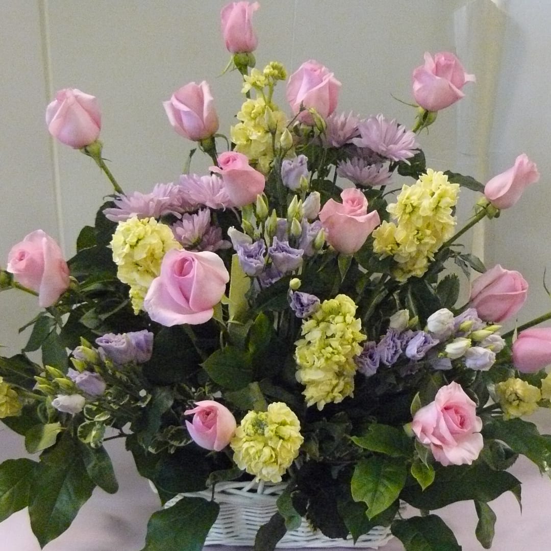 Pink roses and lavender flowers arranged in a white basket