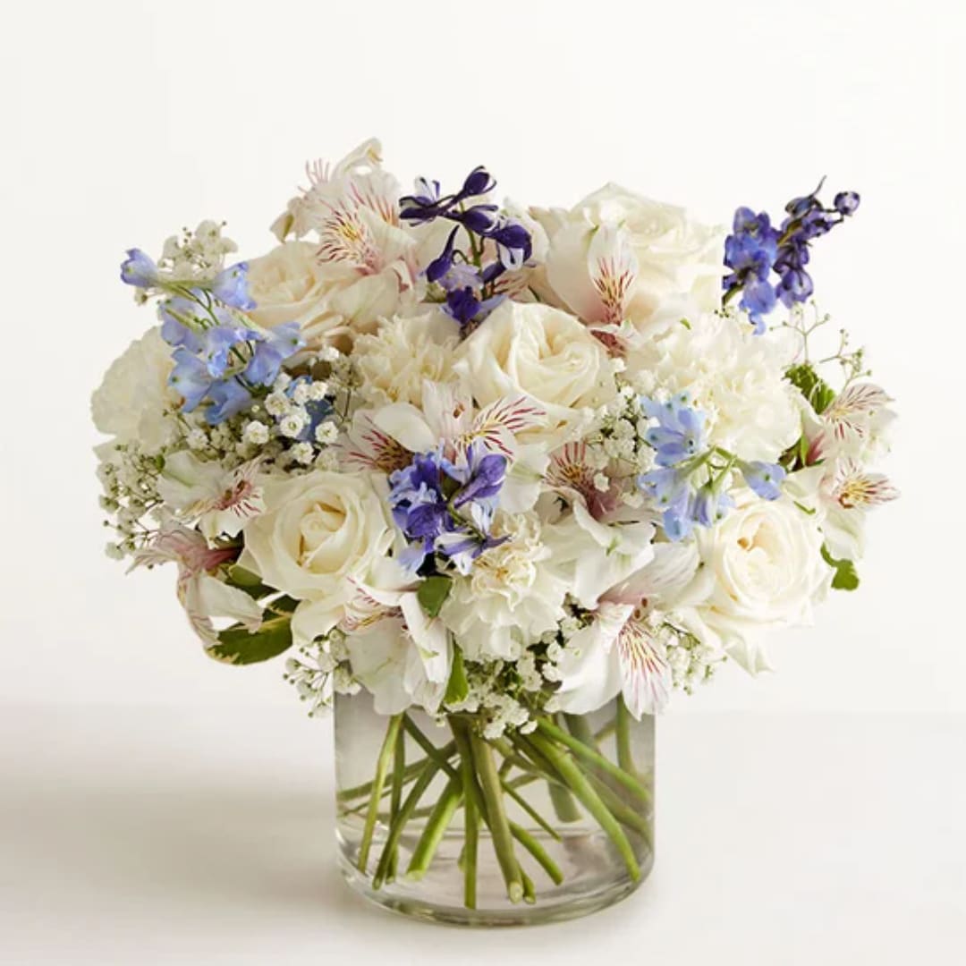 White and blue mixed bouquet in a clear glass vase