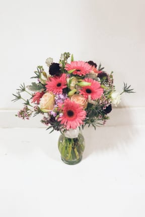 Pink gerbera and peach roses in a glass vase