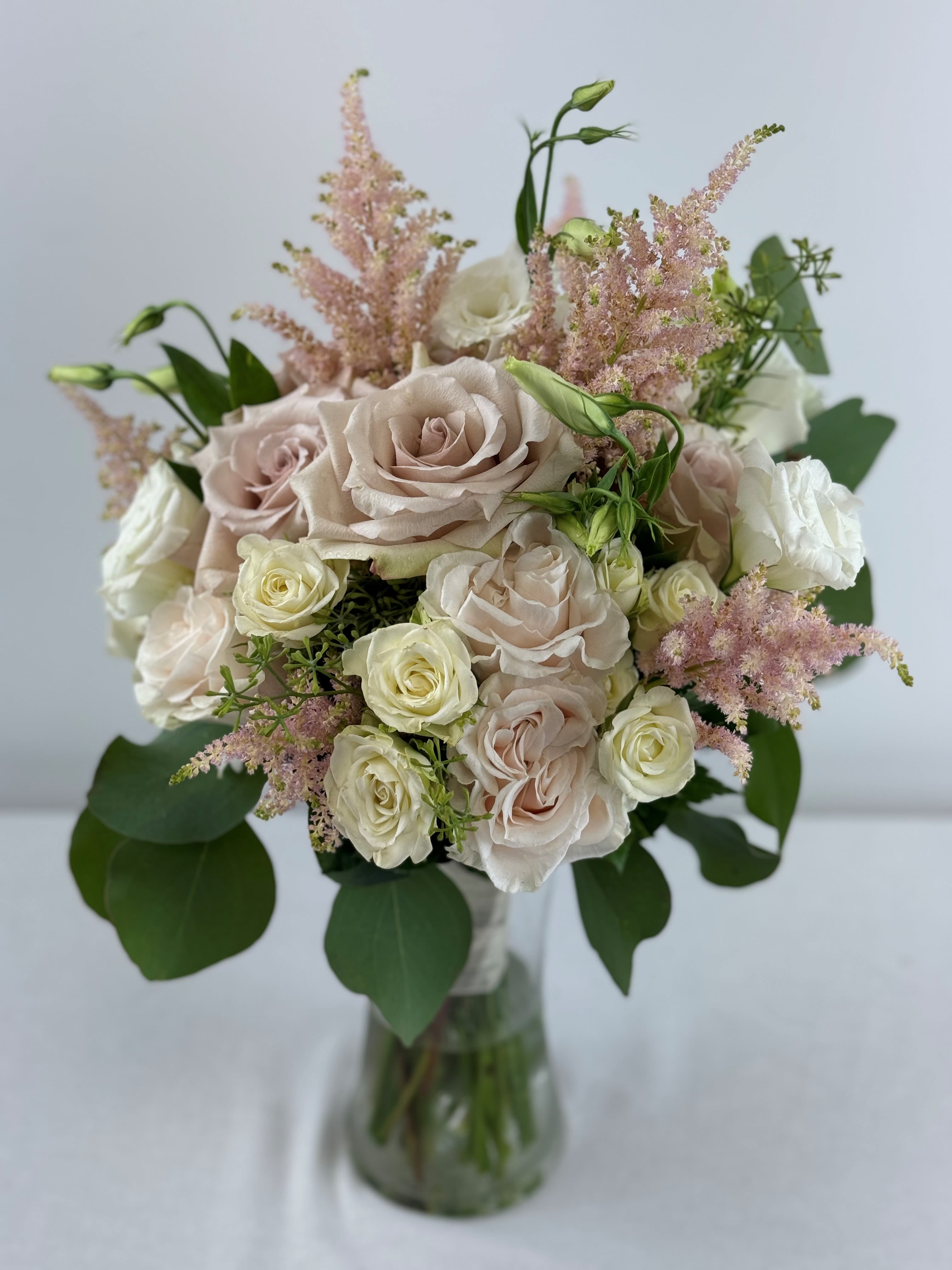 Bouquet of pale roses and pink astilbe in a glass vase