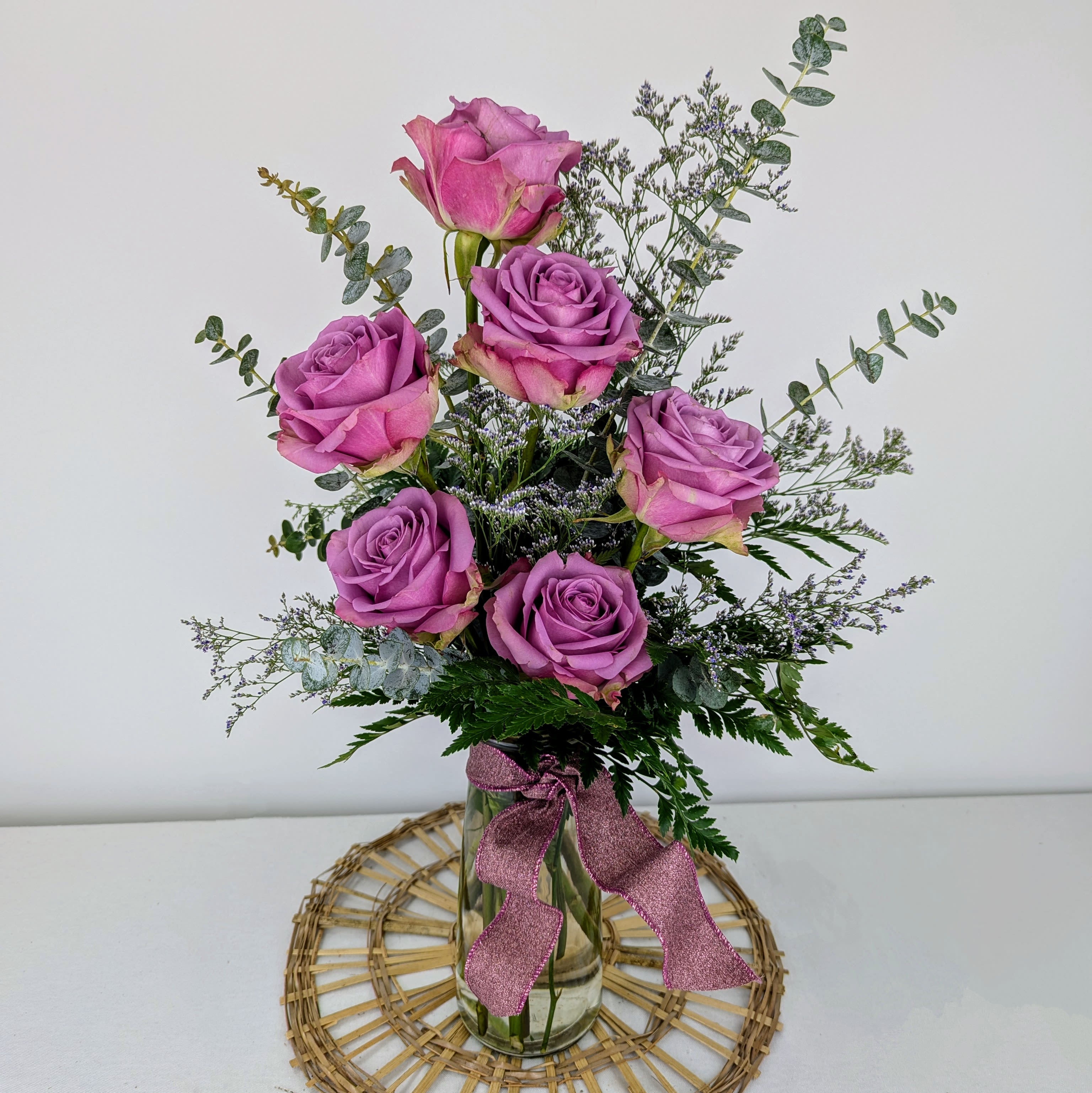 Pink roses arranged in a clear glass vase with a ribbon
