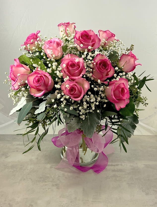 Pink roses arranged in a glass vase with baby's breath