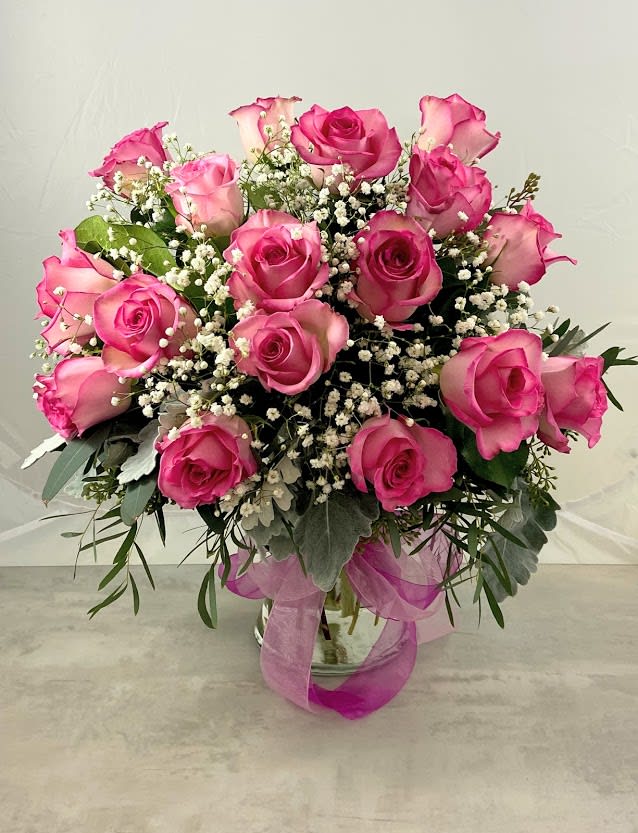 Pink roses arranged in a glass vase with baby's breath
