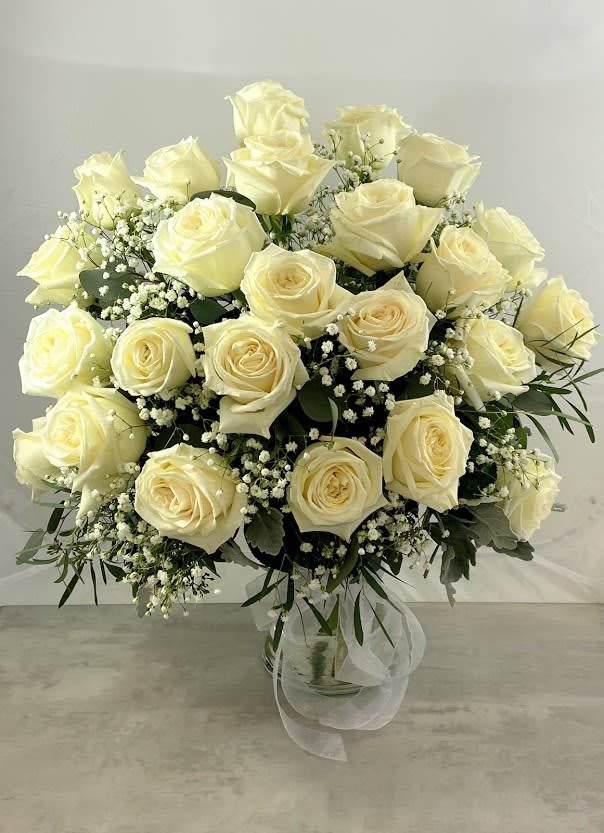 Bouquet of cream roses with baby's breath in a clear glass vase