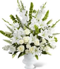White floral arrangement in a white vase with tall green accents