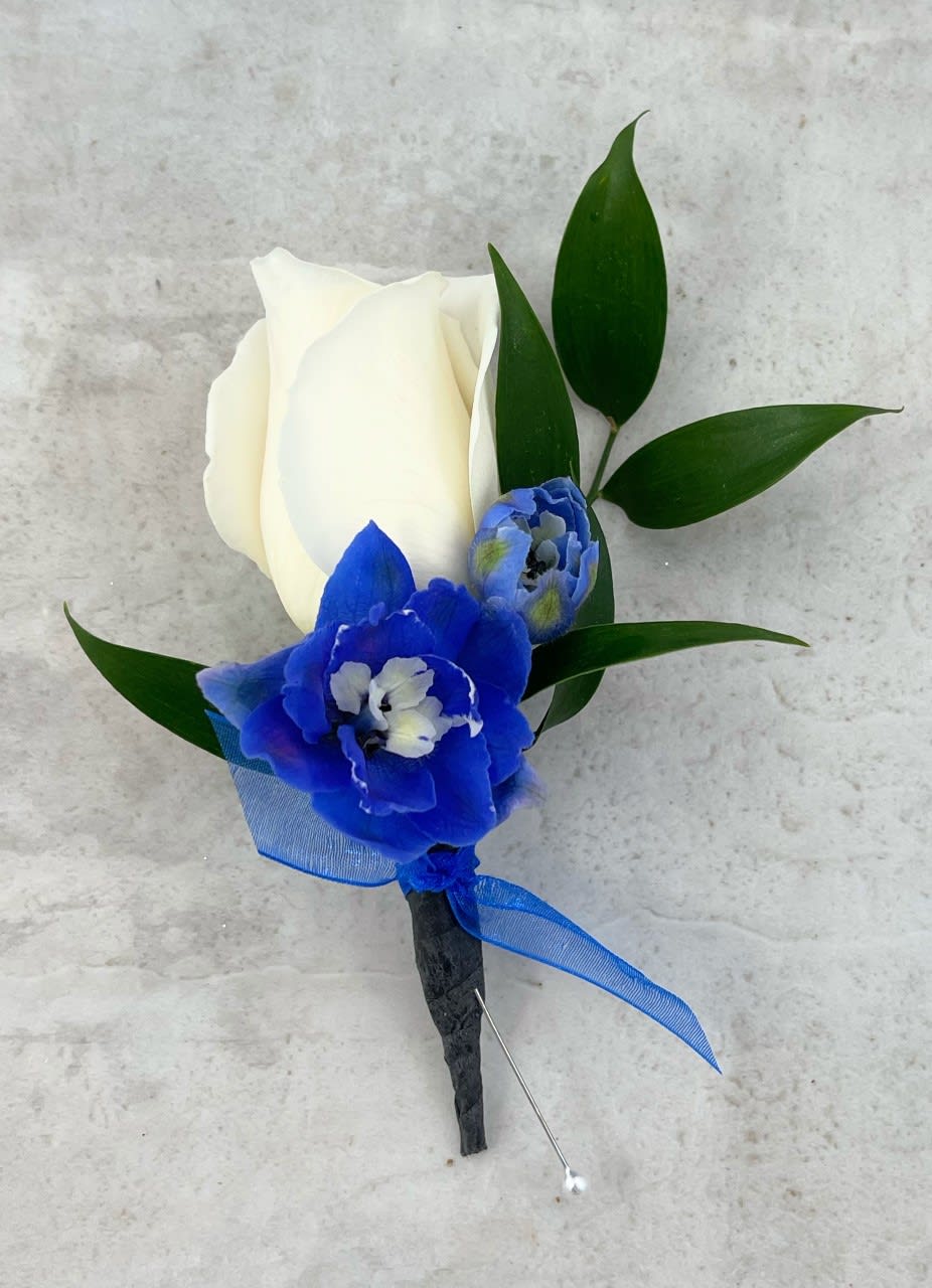 White rose boutonniere with blue flowers and green leaves