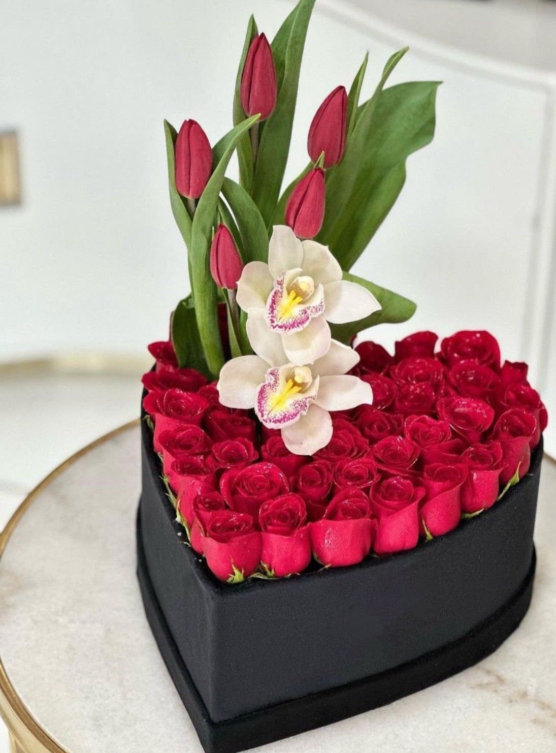 Corazon Elegance Premium - Hermosa caja en forma de corazon con acabado negro elegante ,diseñado con delicada rosas rojas fresas cuidadosamente acomodadas . Este arreglo se complementa con tulipanes de diferentes colores y Una sofisticada orquidea Blanca en el centro,creando una combinacion unica de romanticisismo y lujo