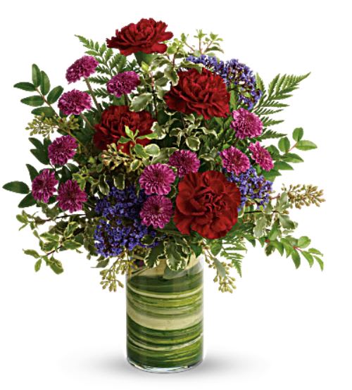 Red and purple flowers arranged in a green glass vase